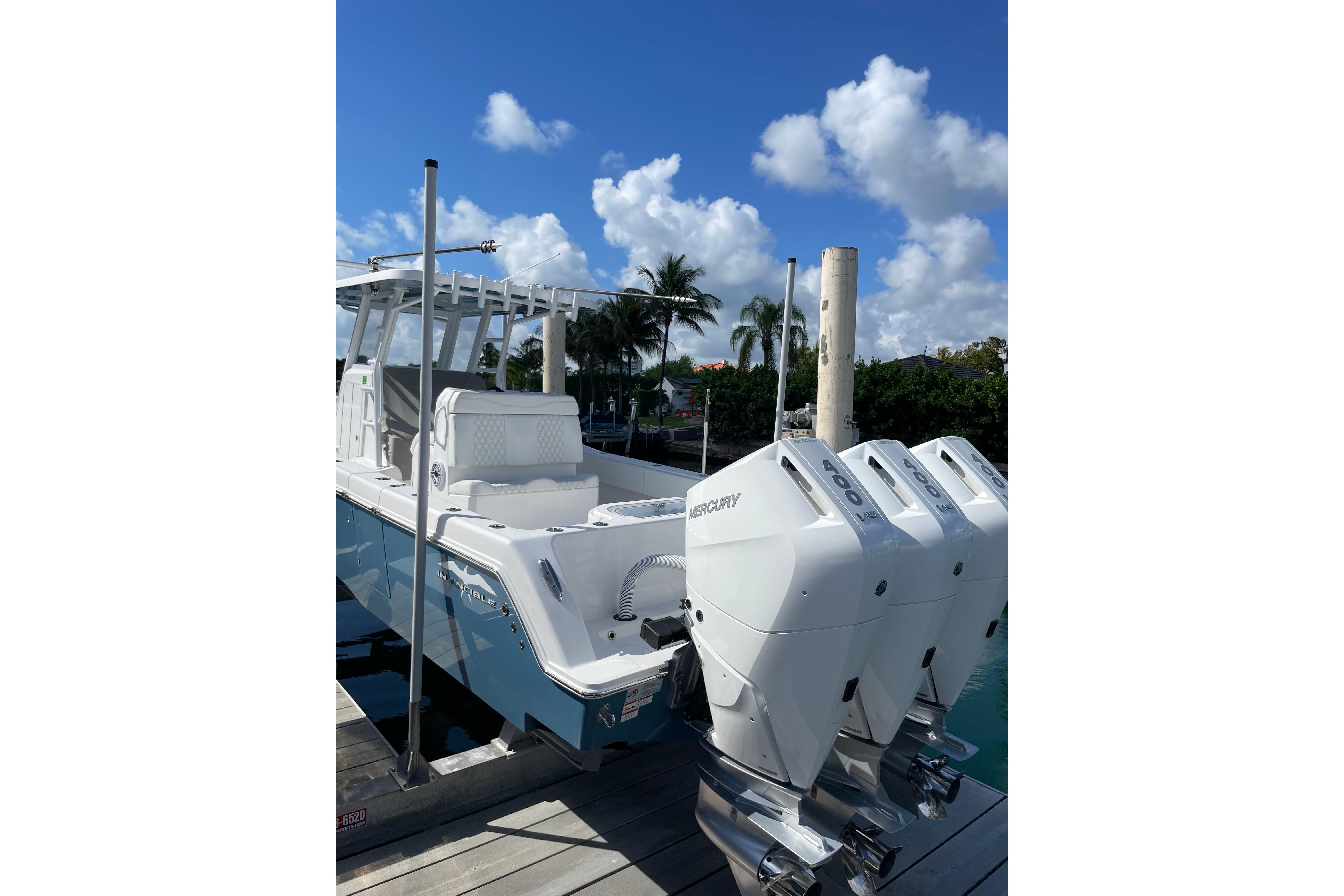 2024 Invincible 36 Open Fisherman boat with triple Mercury engines docked under blue sky.