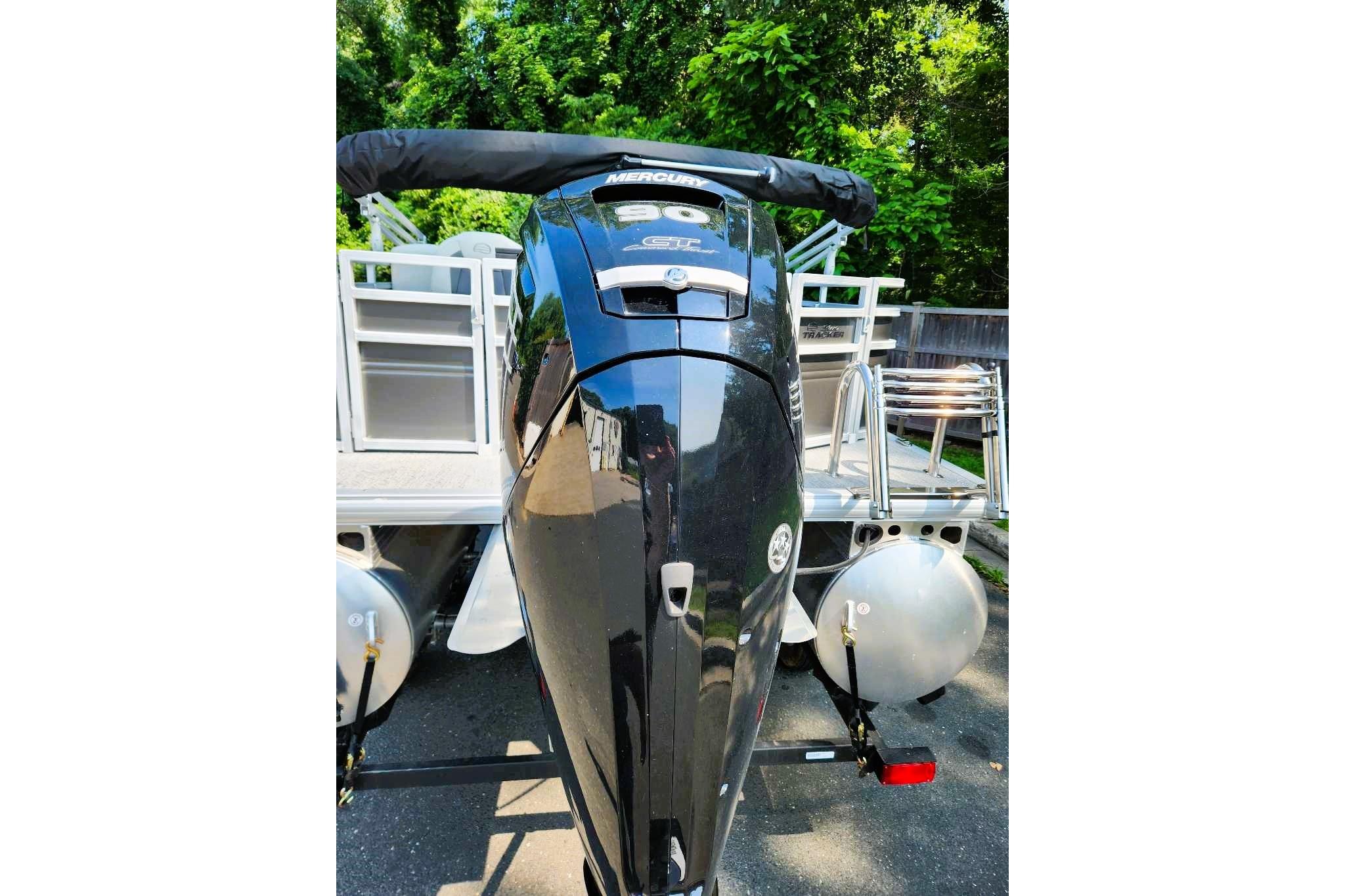 2026 Sun Tracker Fishin' Barge 20 DLX with Mercury outboard motor, parked outdoors.