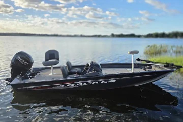 2020 Tracker Pro Team 175 TF boat on a serene lake under a blue sky.