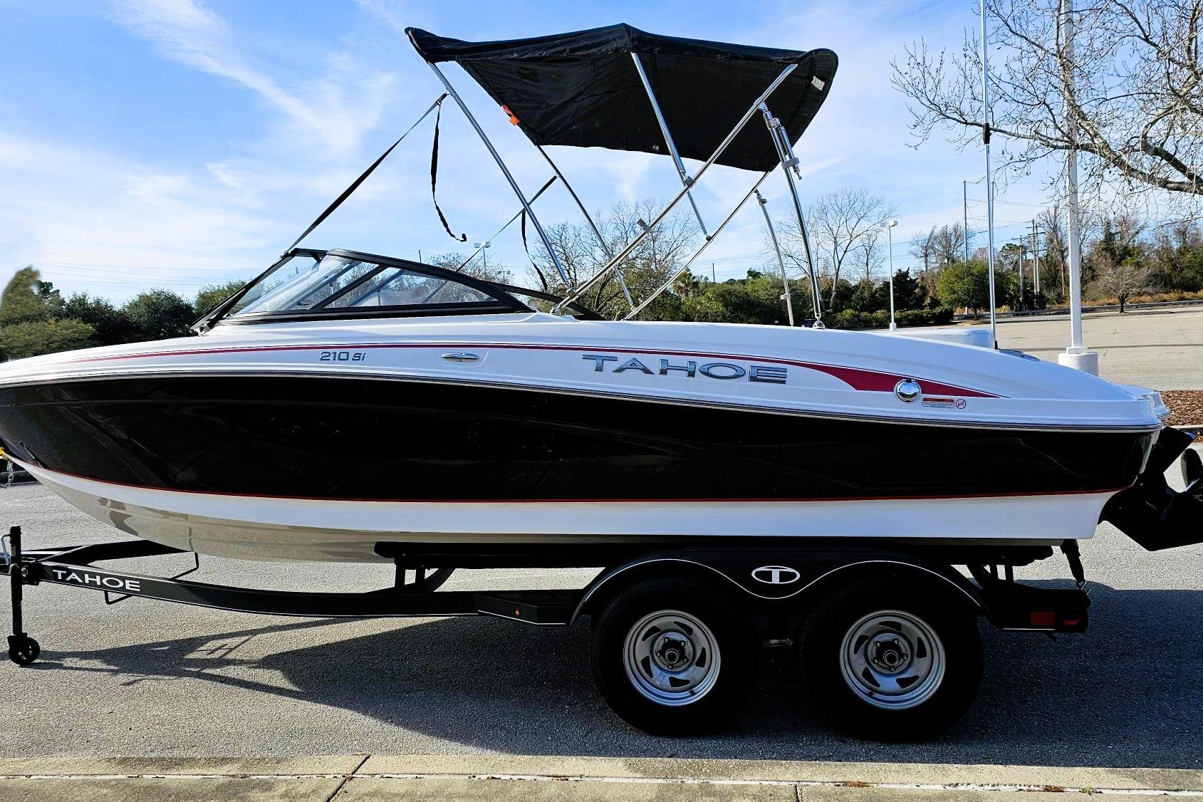 2023 Tahoe 210 Si boat on trailer, black and white design, parked outdoors.