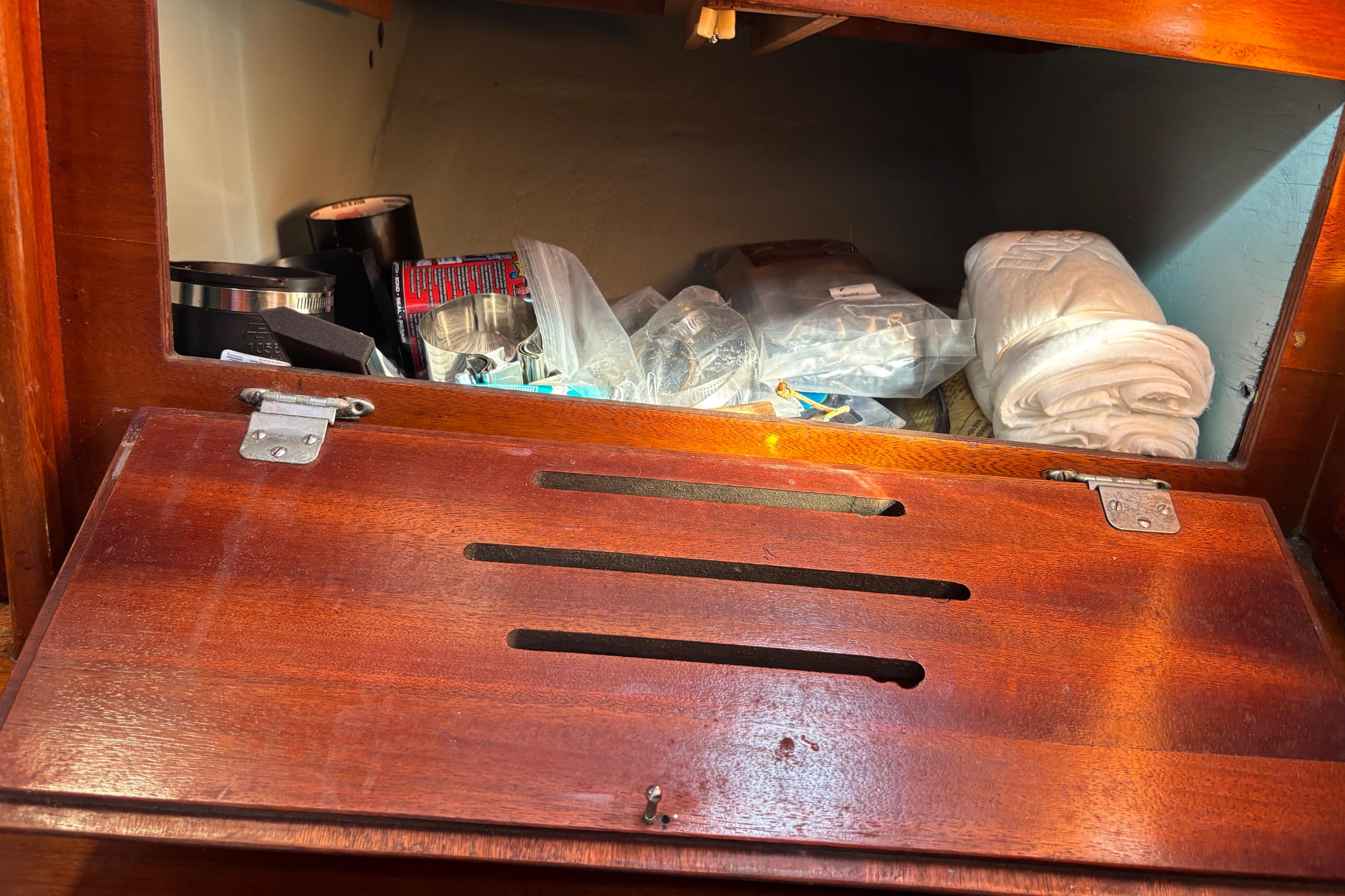 Storage compartment in a 1972 Cape Dory Cape 30 sailboat with various items inside.