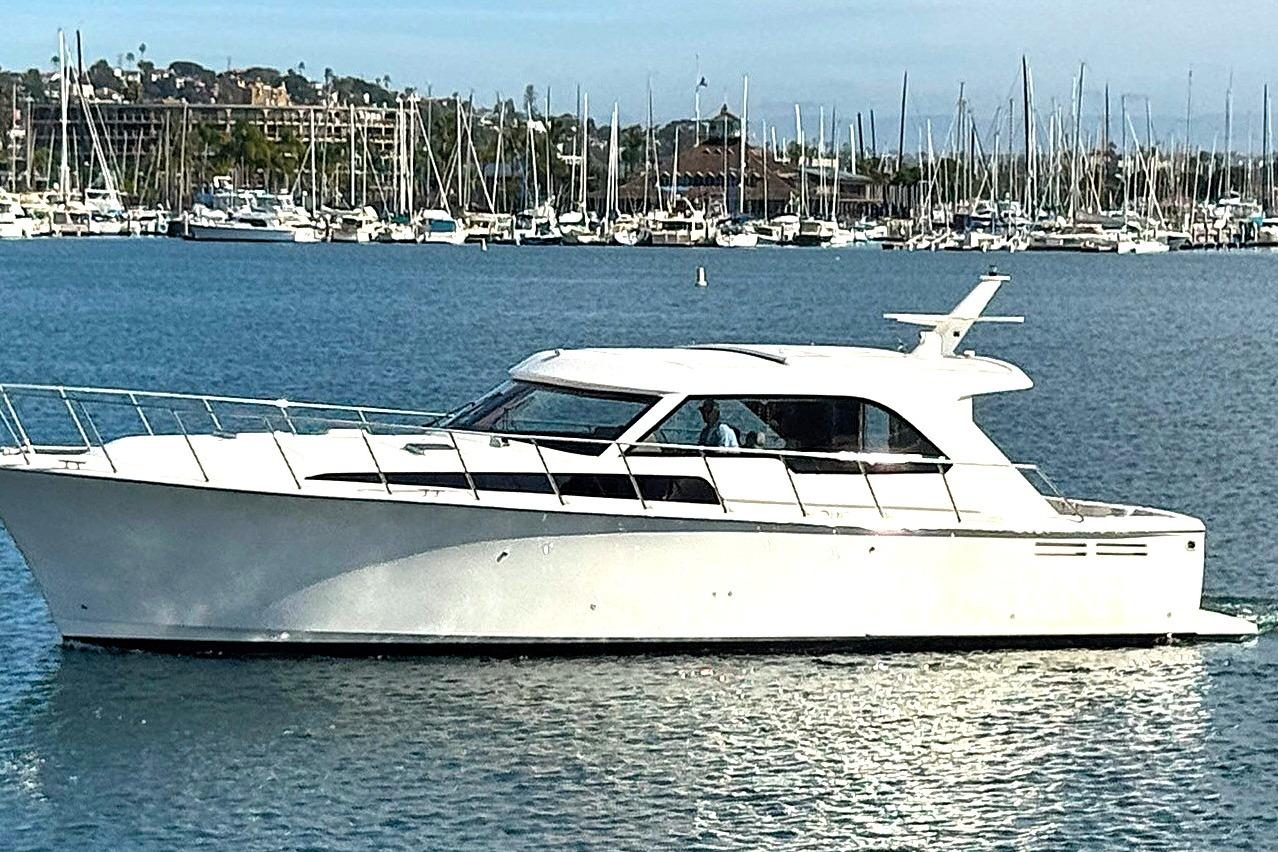 2026 Mikelson Maverick yacht cruising in a marina with sailboats in the background.