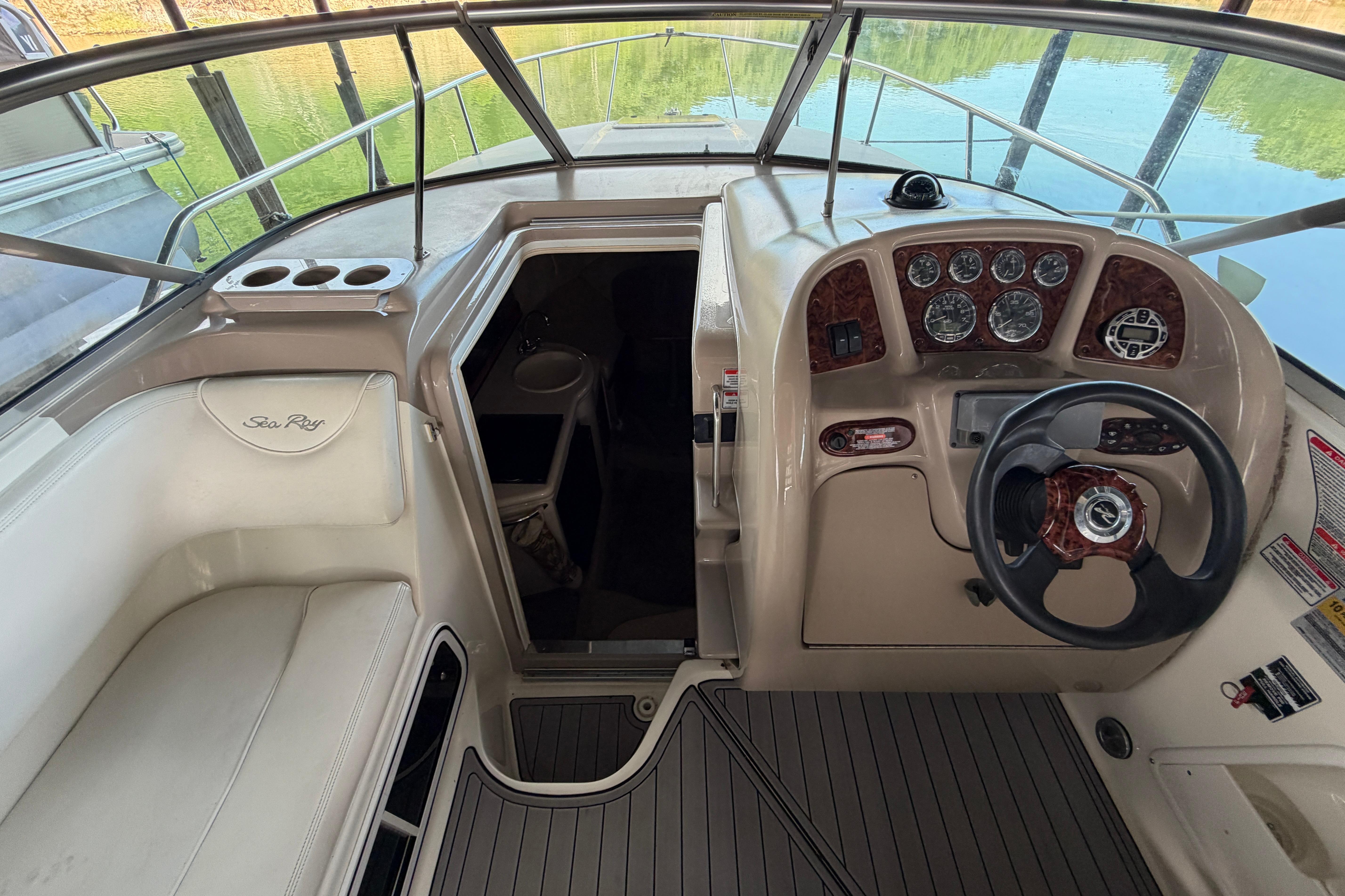 2004 Sea Ray Sundancer 260 cockpit with steering wheel, gauges, and cabin entrance.