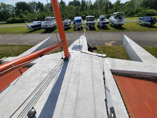 1985 Crowther Buccaneer sailboat on land, surrounded by other boats, with visible orange mast.