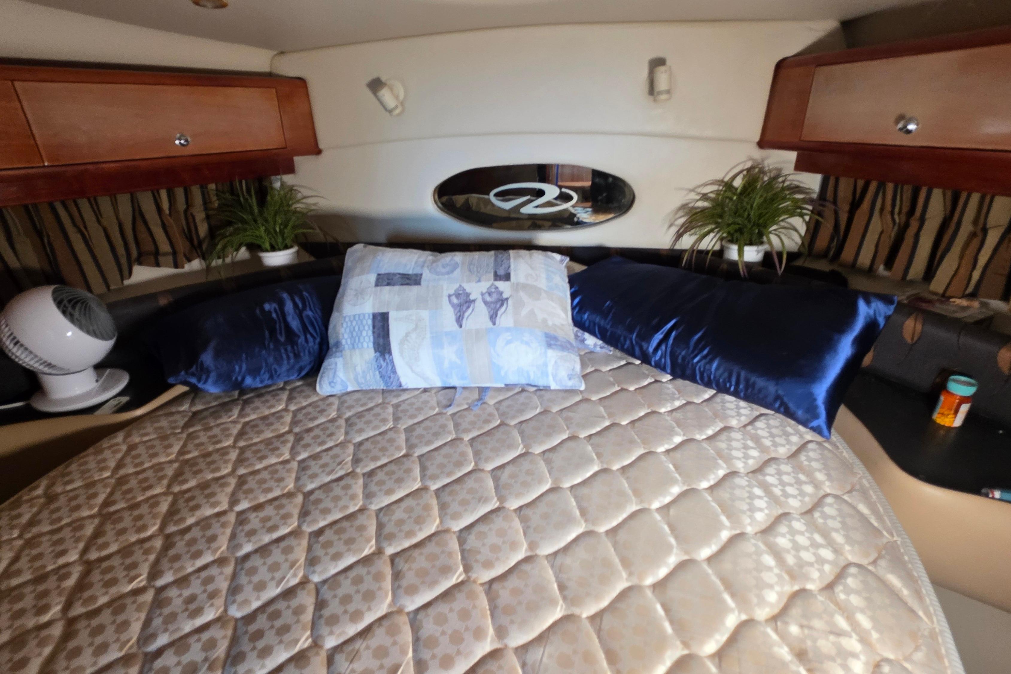 Luxurious cabin interior of 2002 Regal Commodore 4260 yacht with plush bedding and decor.
