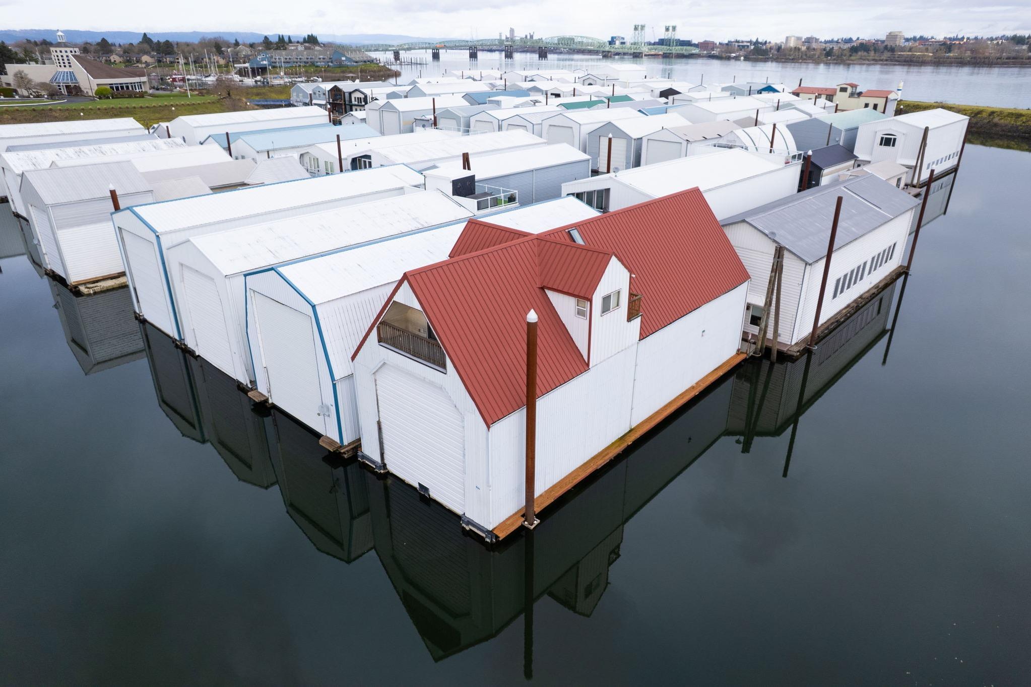 Floating boathouses with red roofs on calm water, Custom model, 1976.