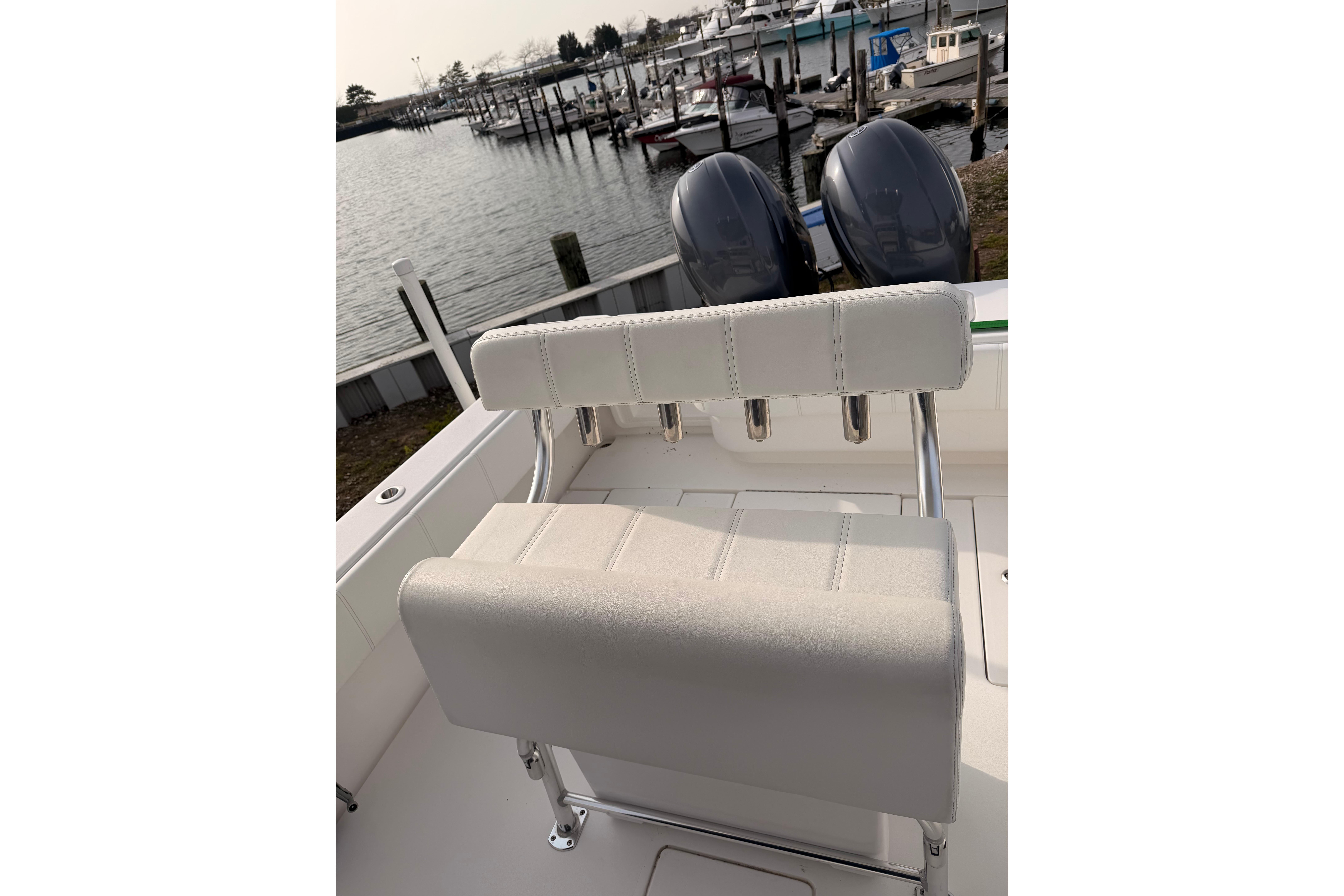 Contender boat with dual engines and white seating at a marina dock.