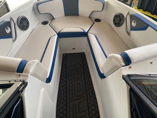 Interior view of a 2024 Scarab 195 ID with white and blue upholstery and speakers.