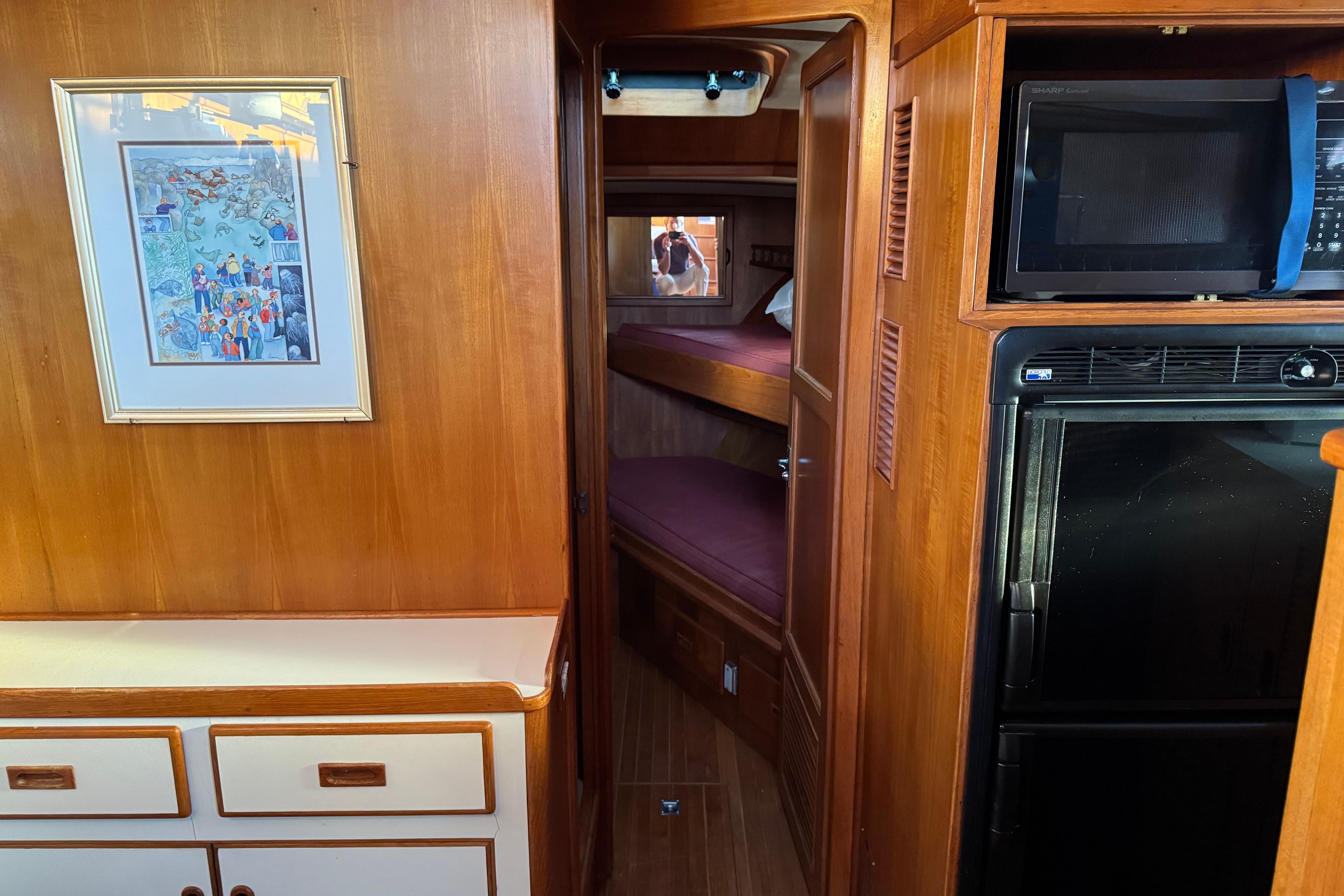Interior of a 1987 President 37 yacht with wood paneling, bunk beds, and kitchen appliances.