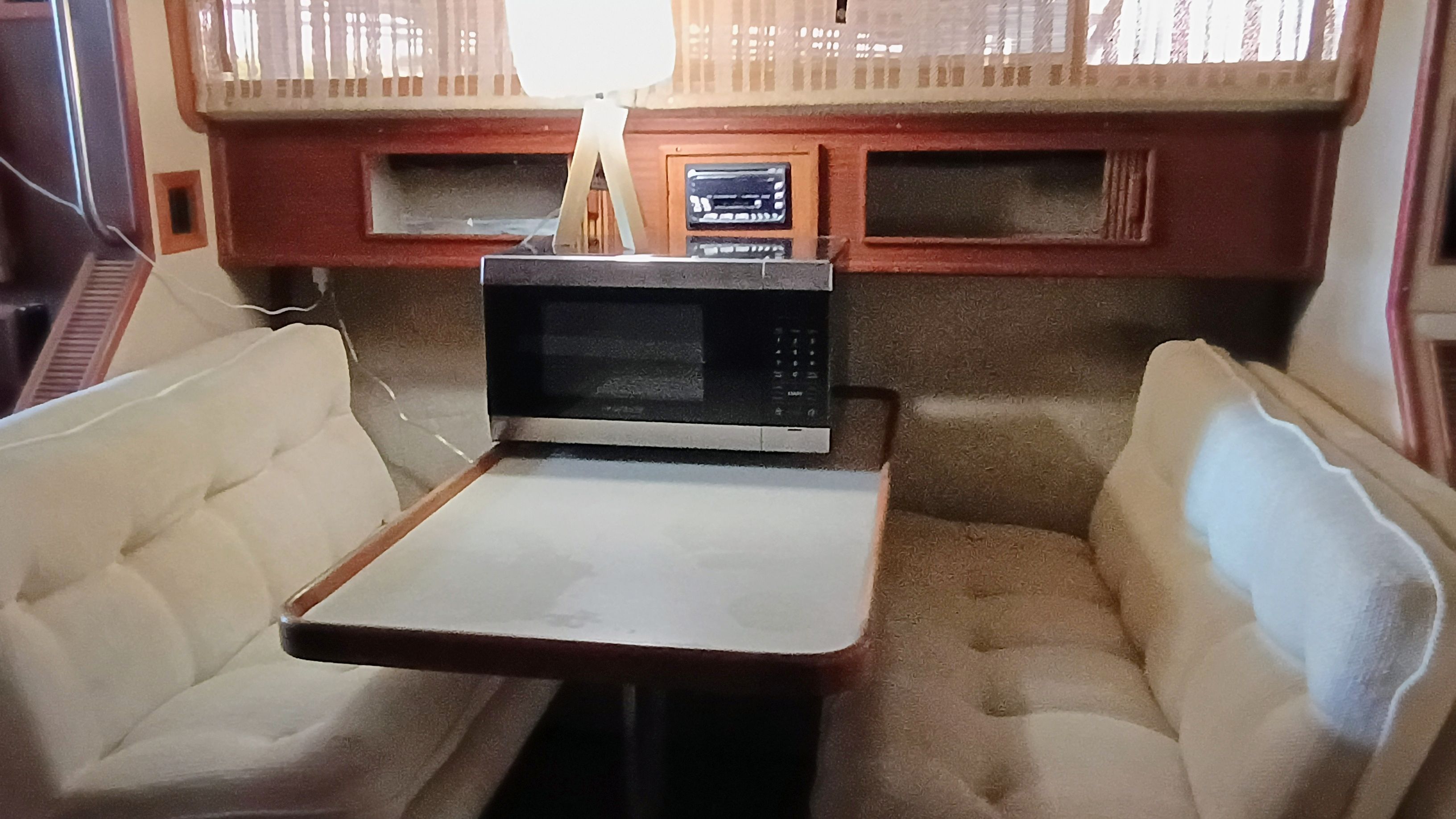 The interior of a 1986 Sea Ray Sundancer features a cozy seating area with a table and microwave.