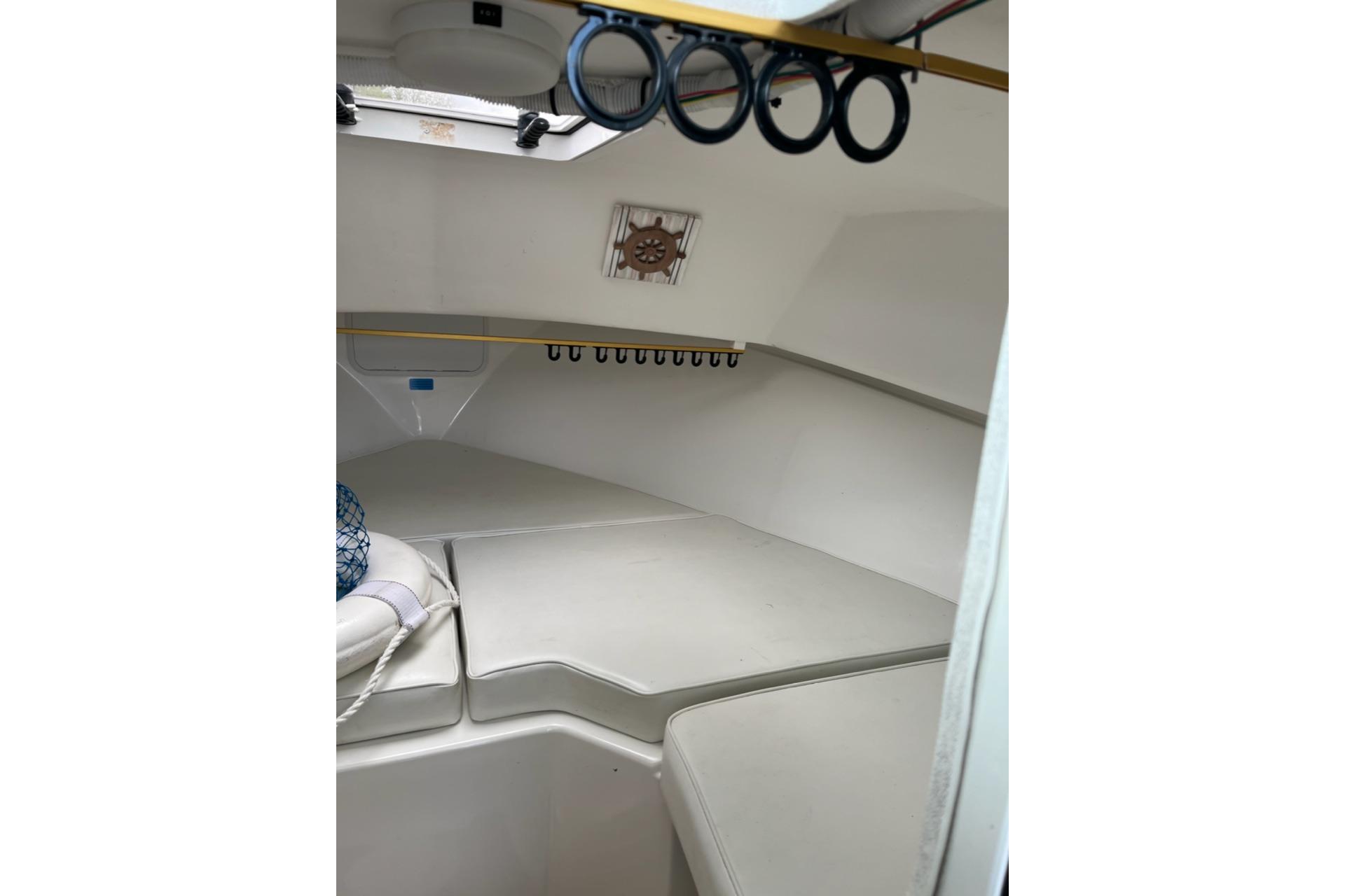 Interior cabin of 2012 Steiger Craft Miami boat, featuring cushioned seating and storage hooks.