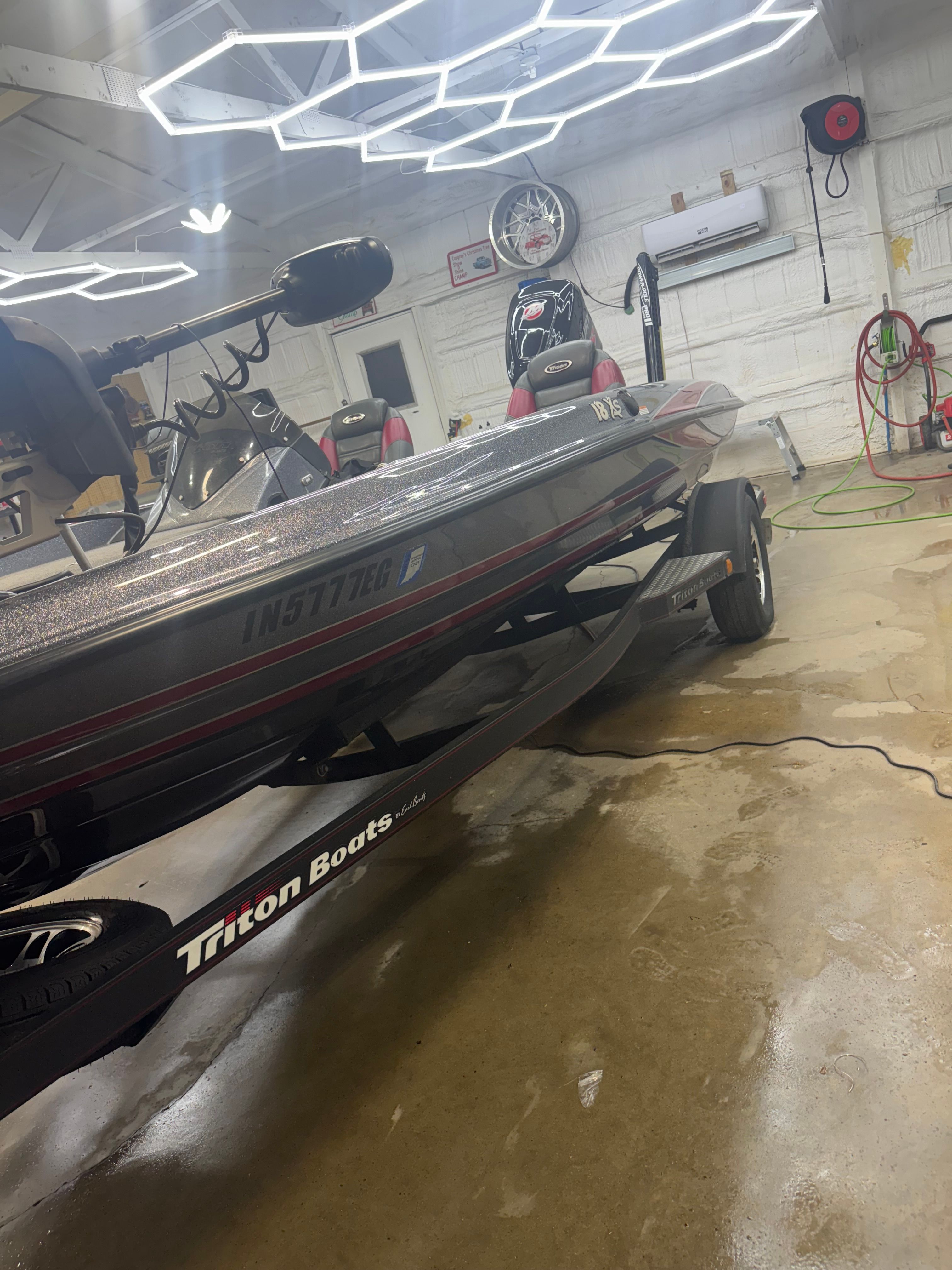 A 2015 Triton 18XS boat is in a garage, mounted on a trailer.