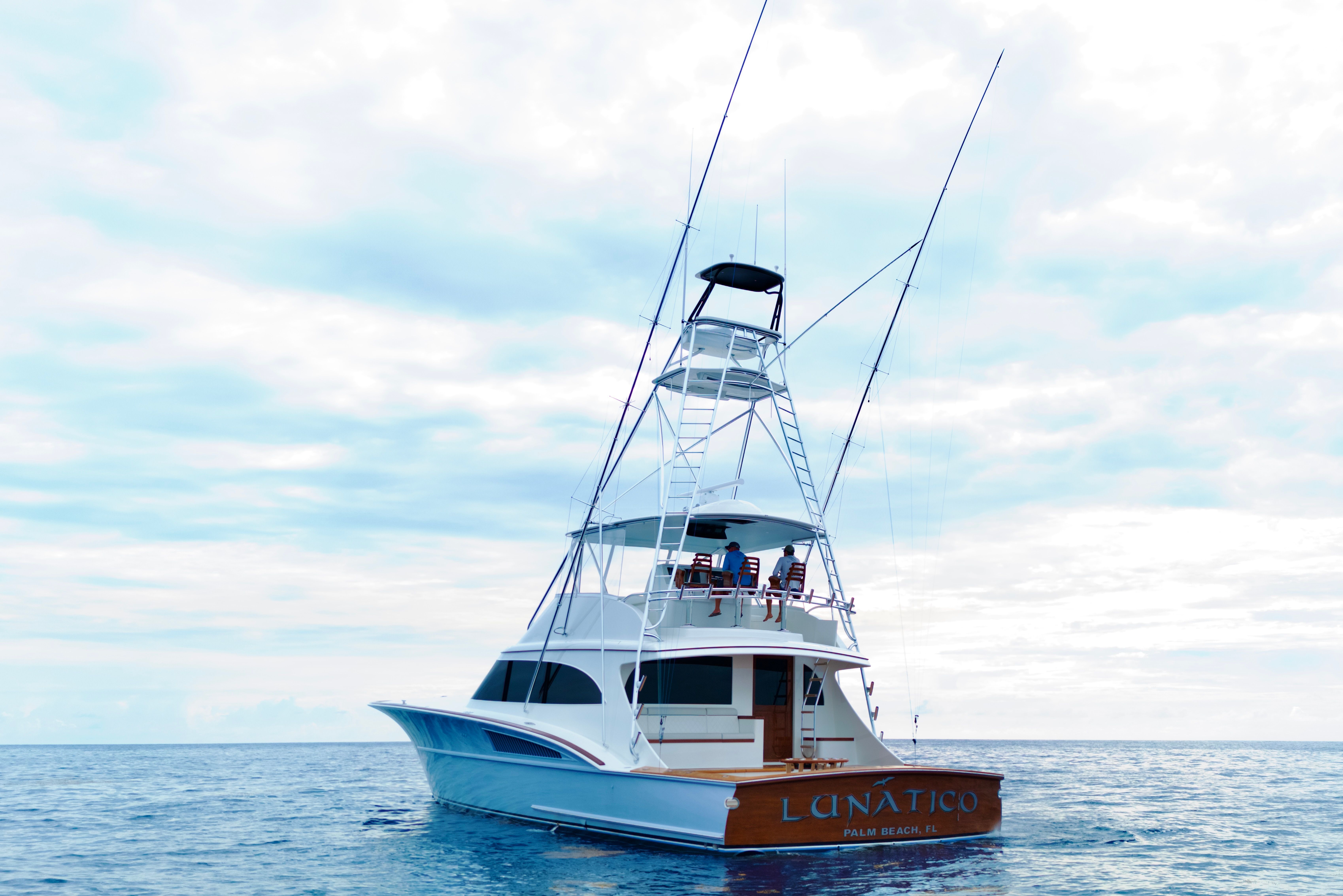 A modern sportfishing boat with a tall tower on calm water.