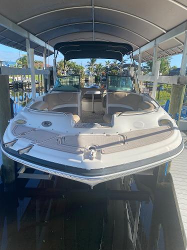 2015 Hurricane SunDeck 2400 OB boat docked under a canopy.