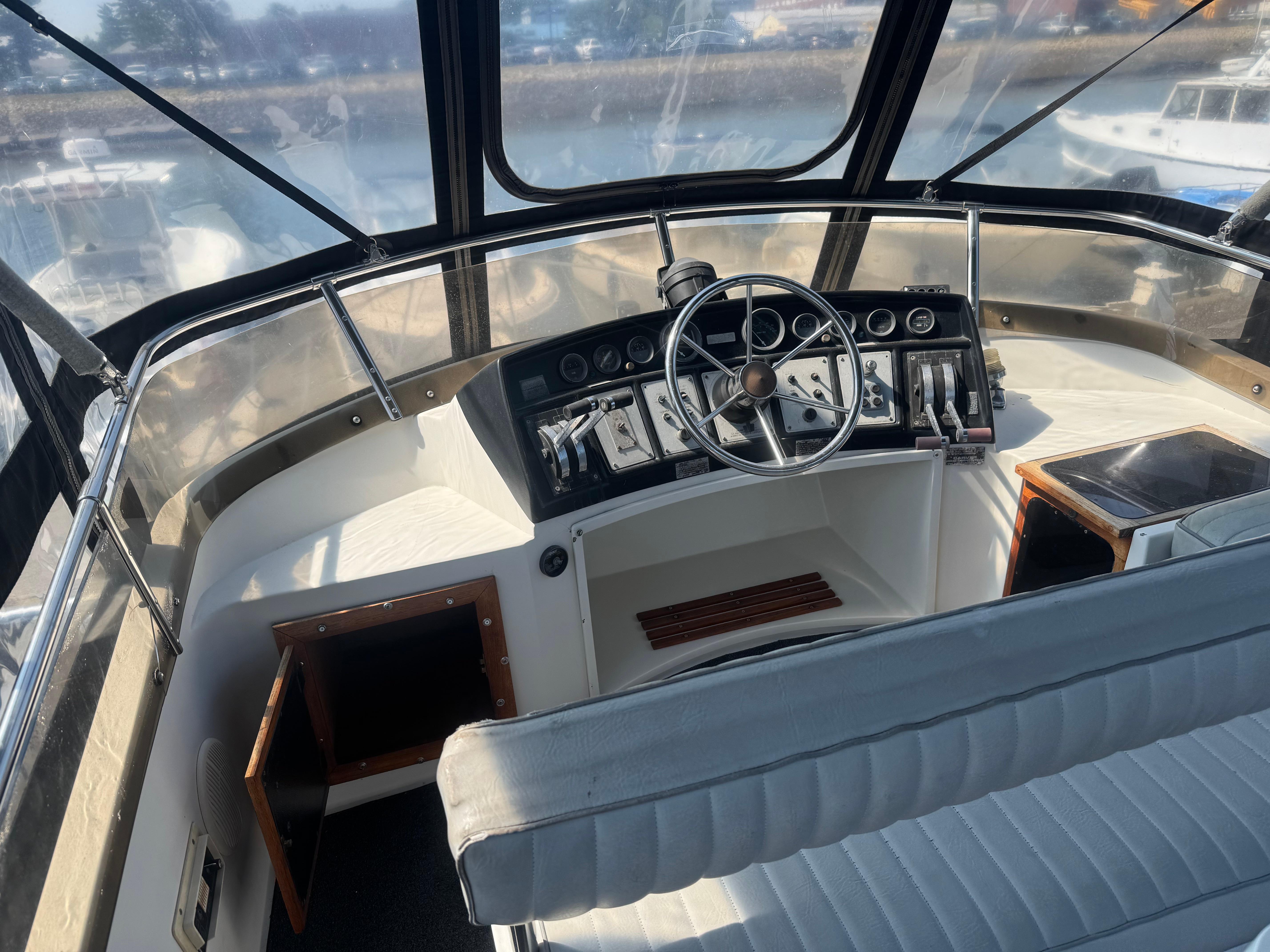Interior helm of 1986 Carver Mariner 28 boat with steering wheel and control panel.