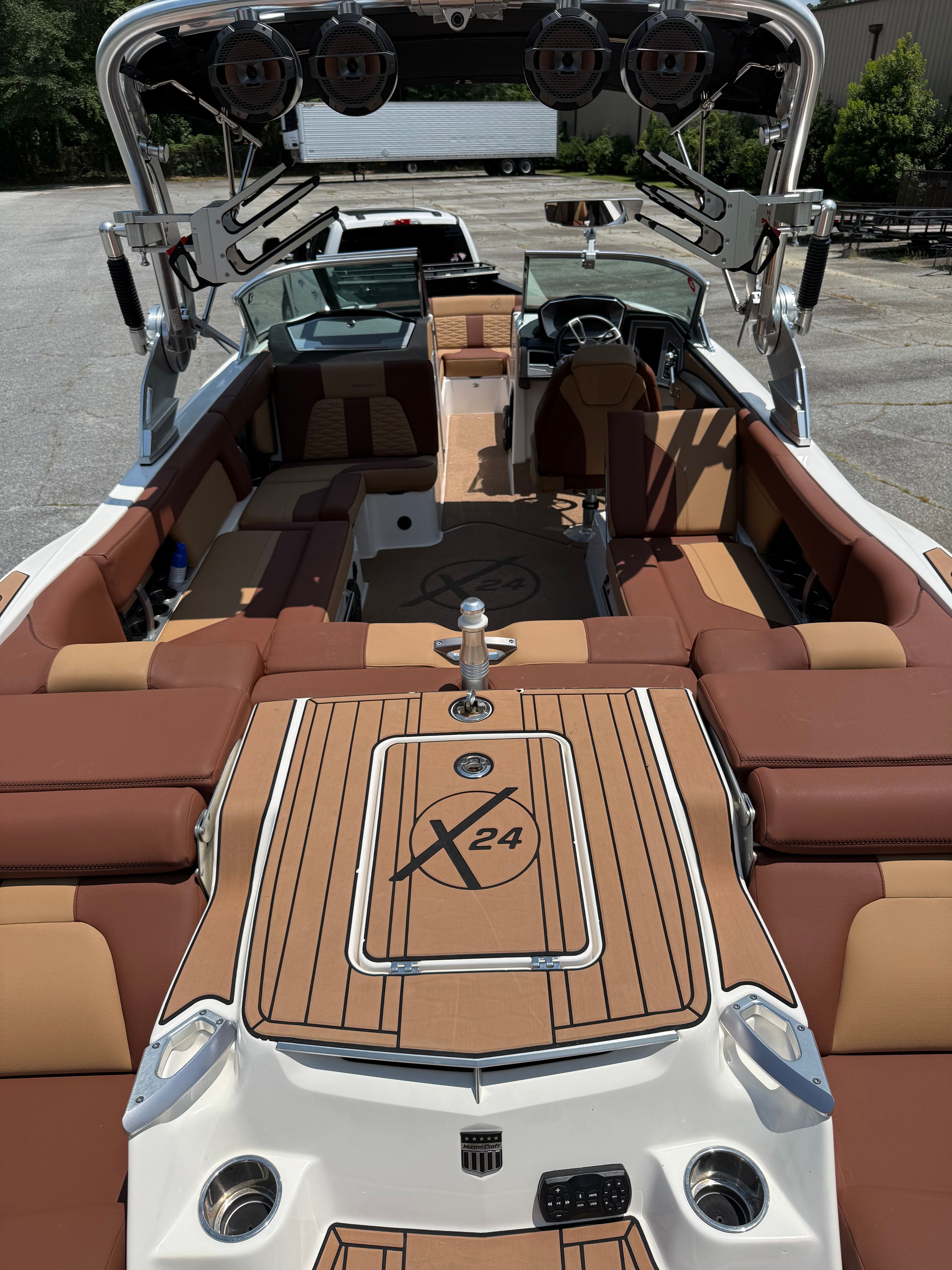 The image shows the interior of a 2021 MasterCraft X24 boat with brown seating and sleek design.