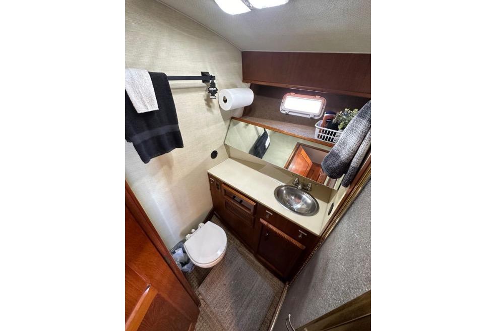 Bathroom interior of 1985 Egg Harbor 33 Sedan yacht, featuring sink, toilet, and storage.
