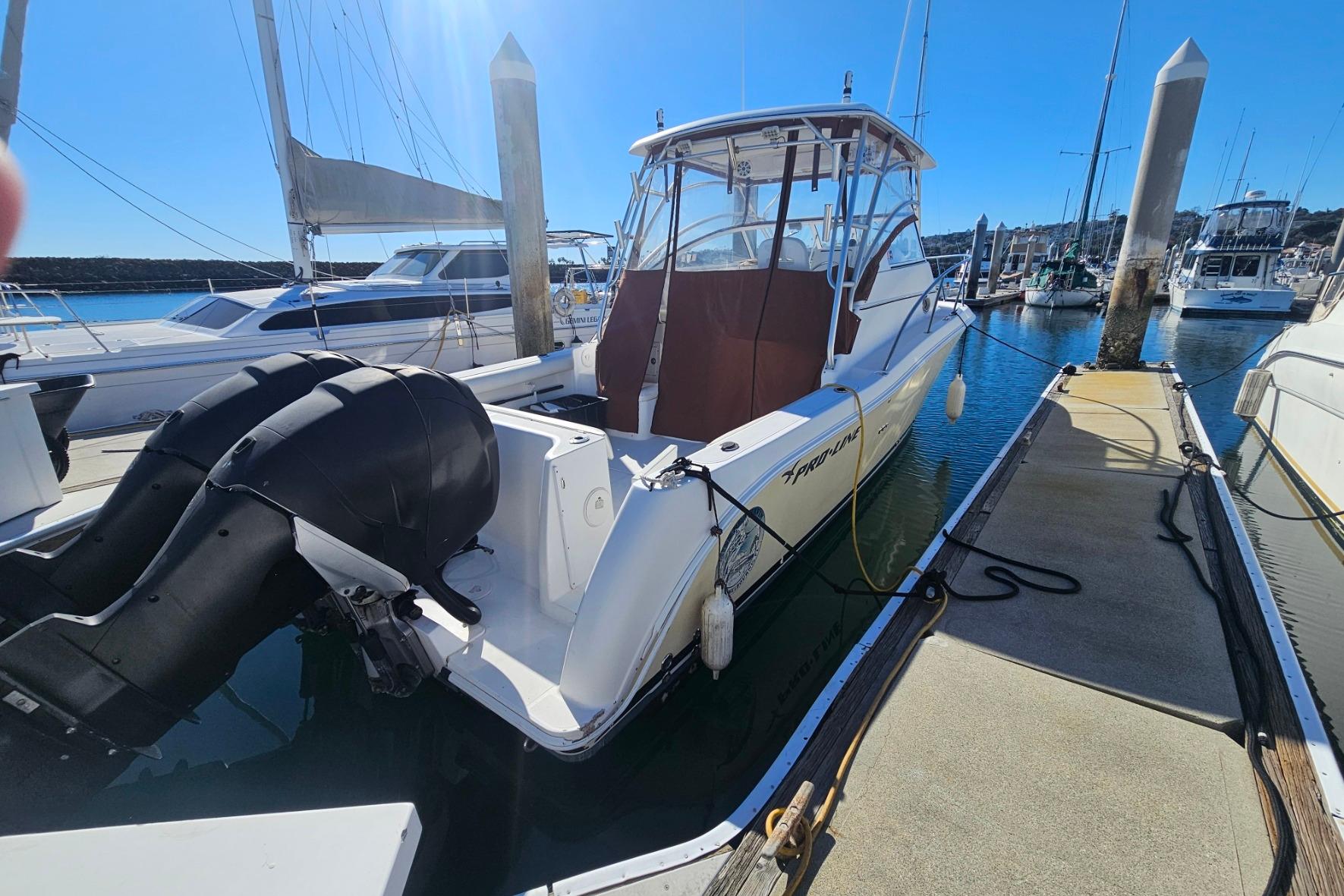 2006 Pro-Line 32 Express boat docked at marina, featuring dual outboard motors.