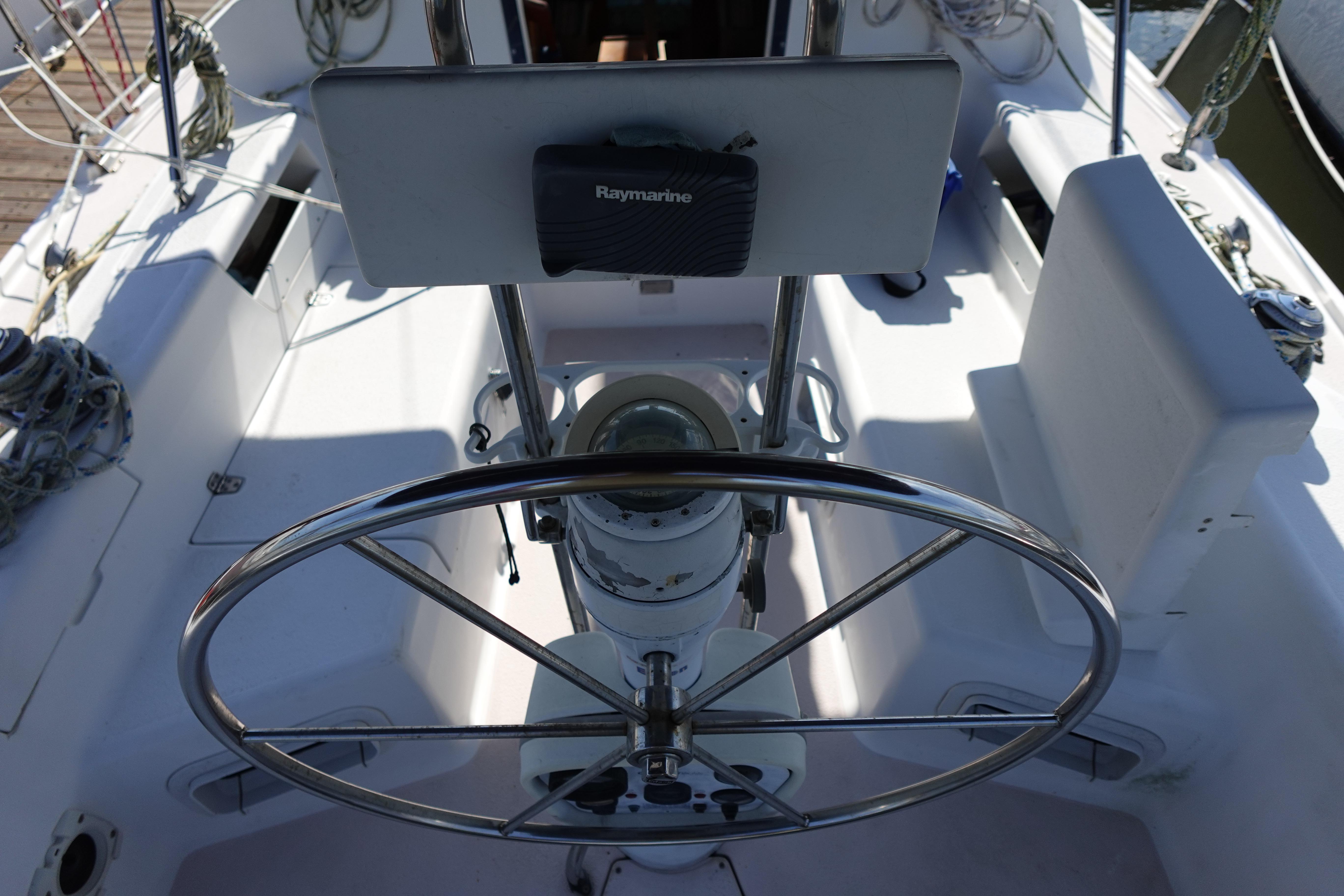 Steering wheel and cockpit of a 1997 Catalina 28 sailboat with navigation equipment.