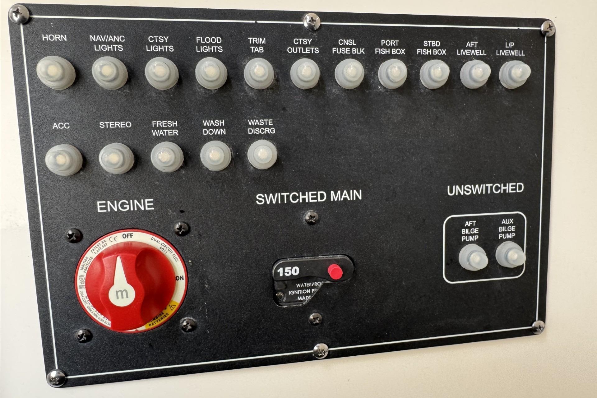 Control panel of a 2024 Boston Whaler 230 Outrage boat with various switches and dials.