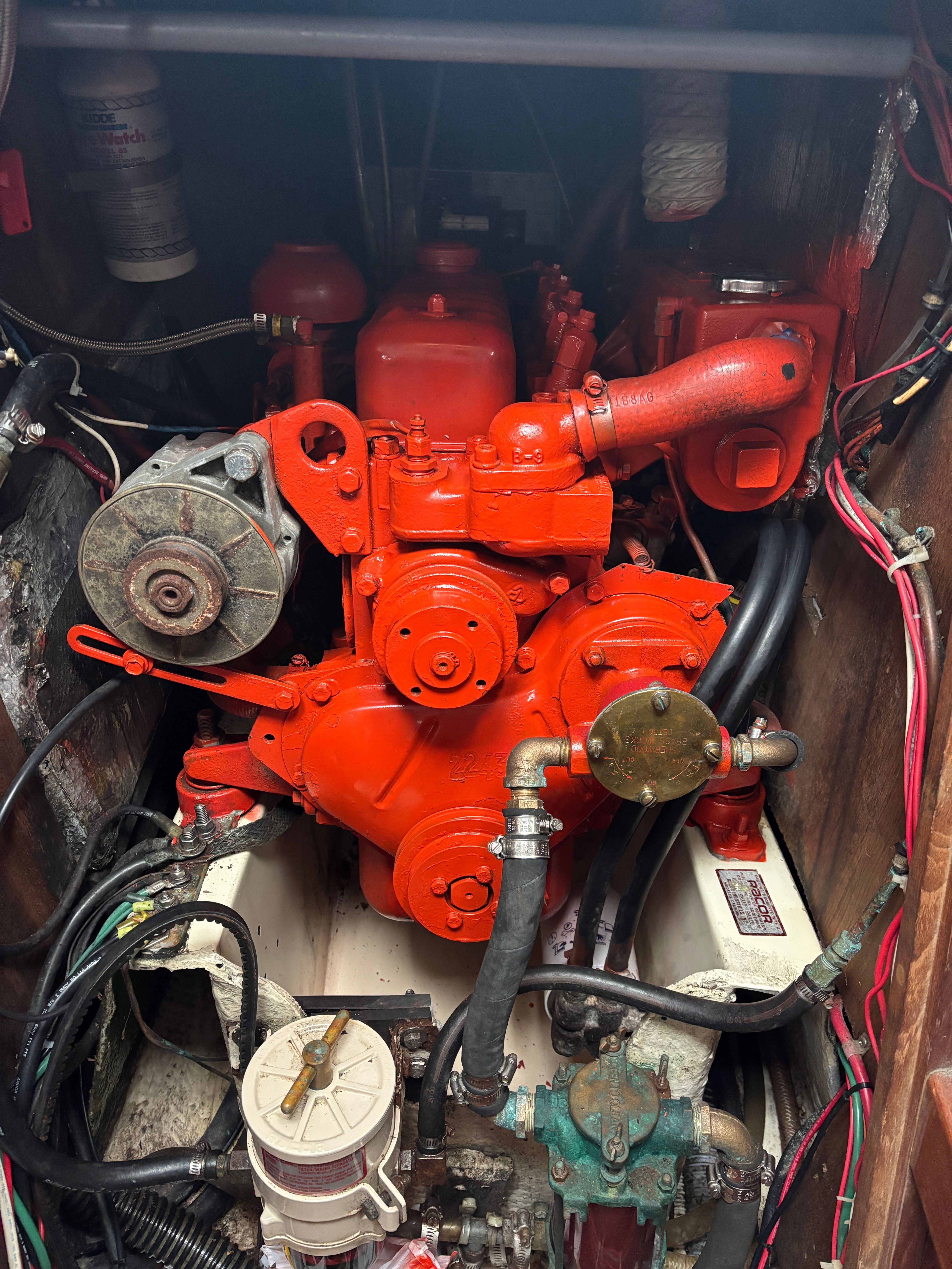 A bright red engine in a boat's engine compartment with various hoses and wires.
