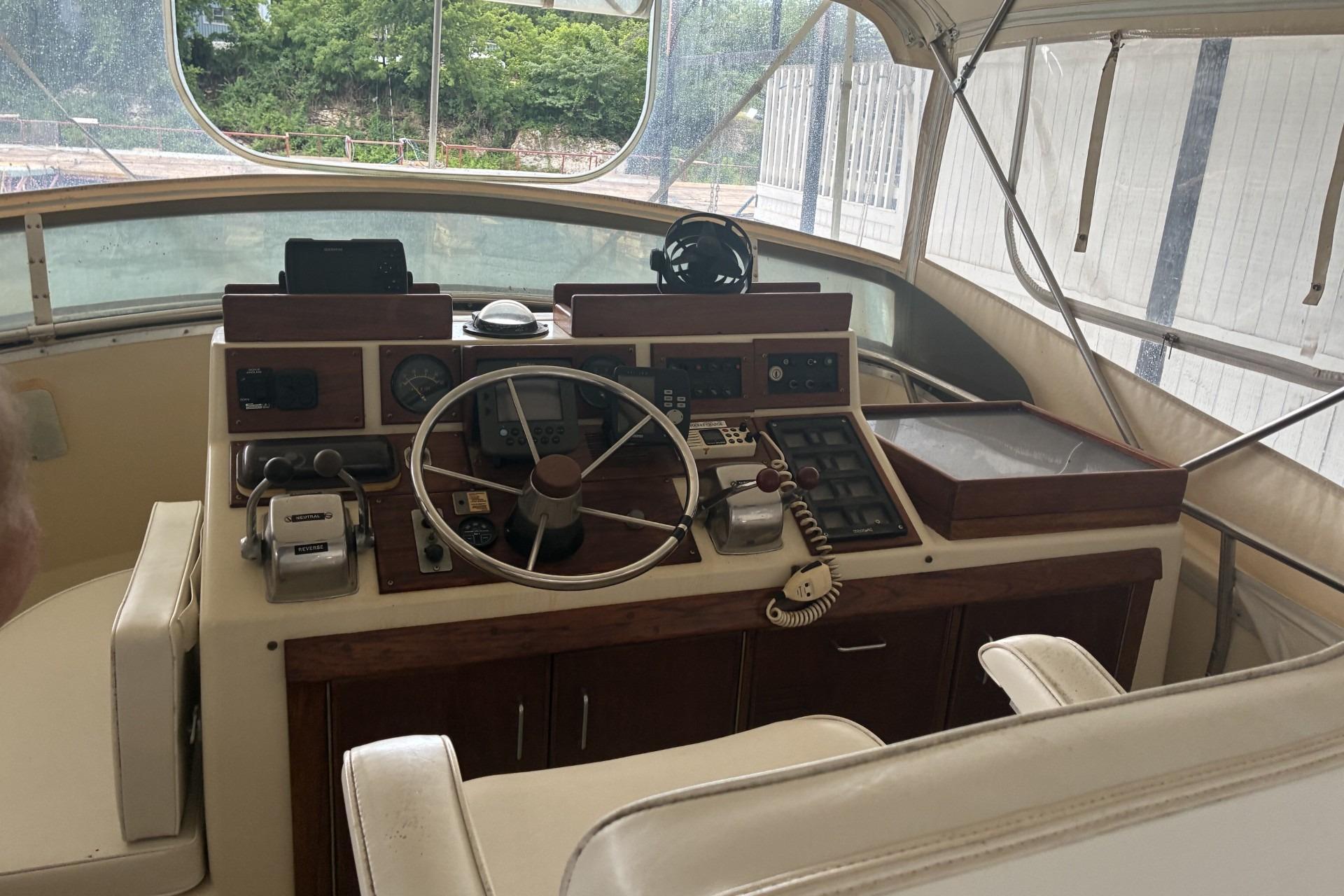 1980 Chris-Craft 360 Commander helm with classic controls and steering wheel in enclosed cockpit.