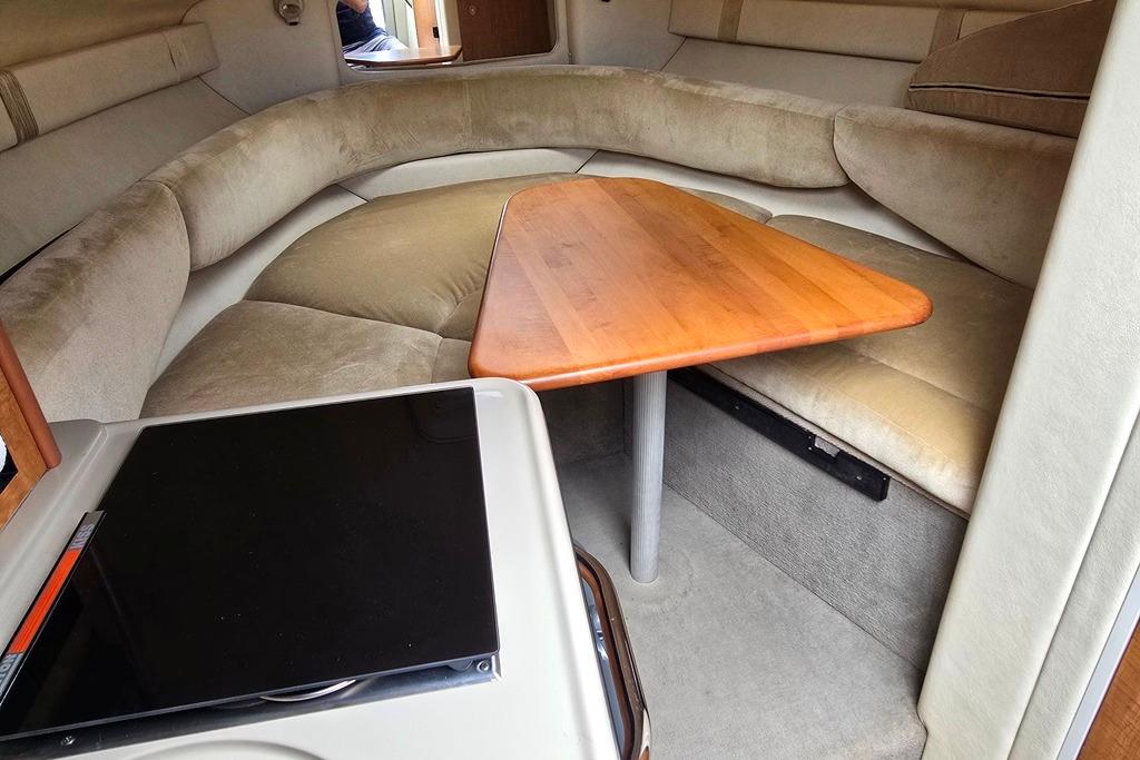 2006 Sea Ray 240 Sundancer cabin interior with cushioned seating and wooden table.