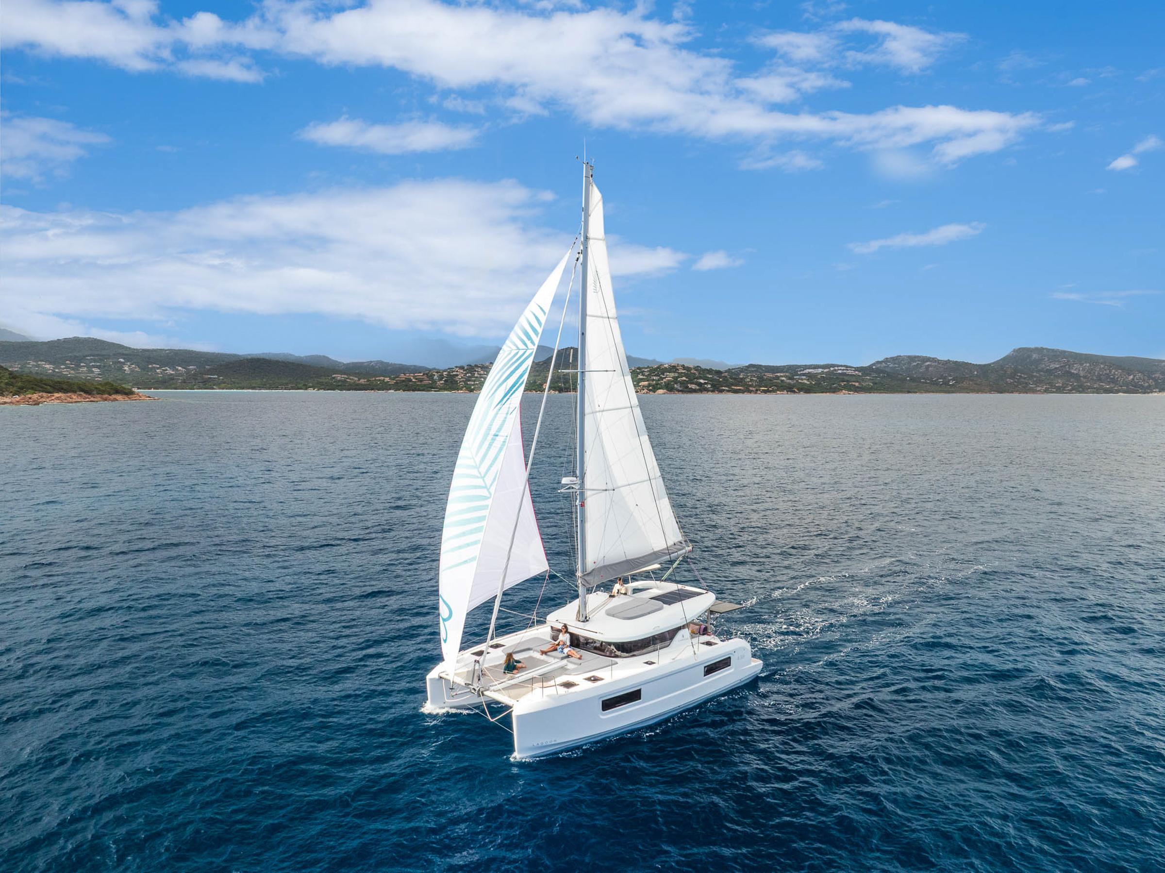 2025 Lagoon 38 catamaran sailing on open sea under clear blue sky.