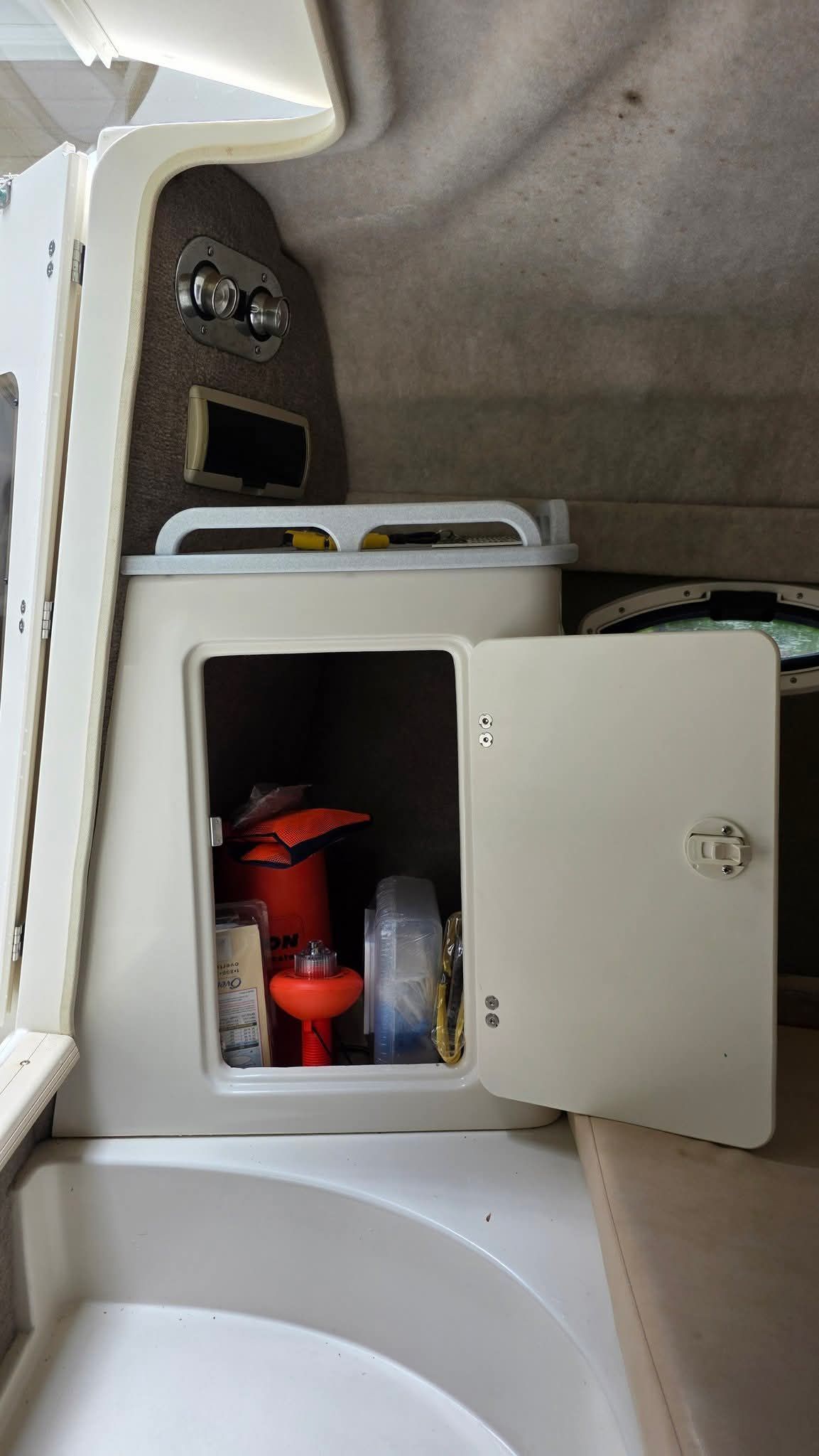 Interior of a boat with an open cabinet showing safety equipment.