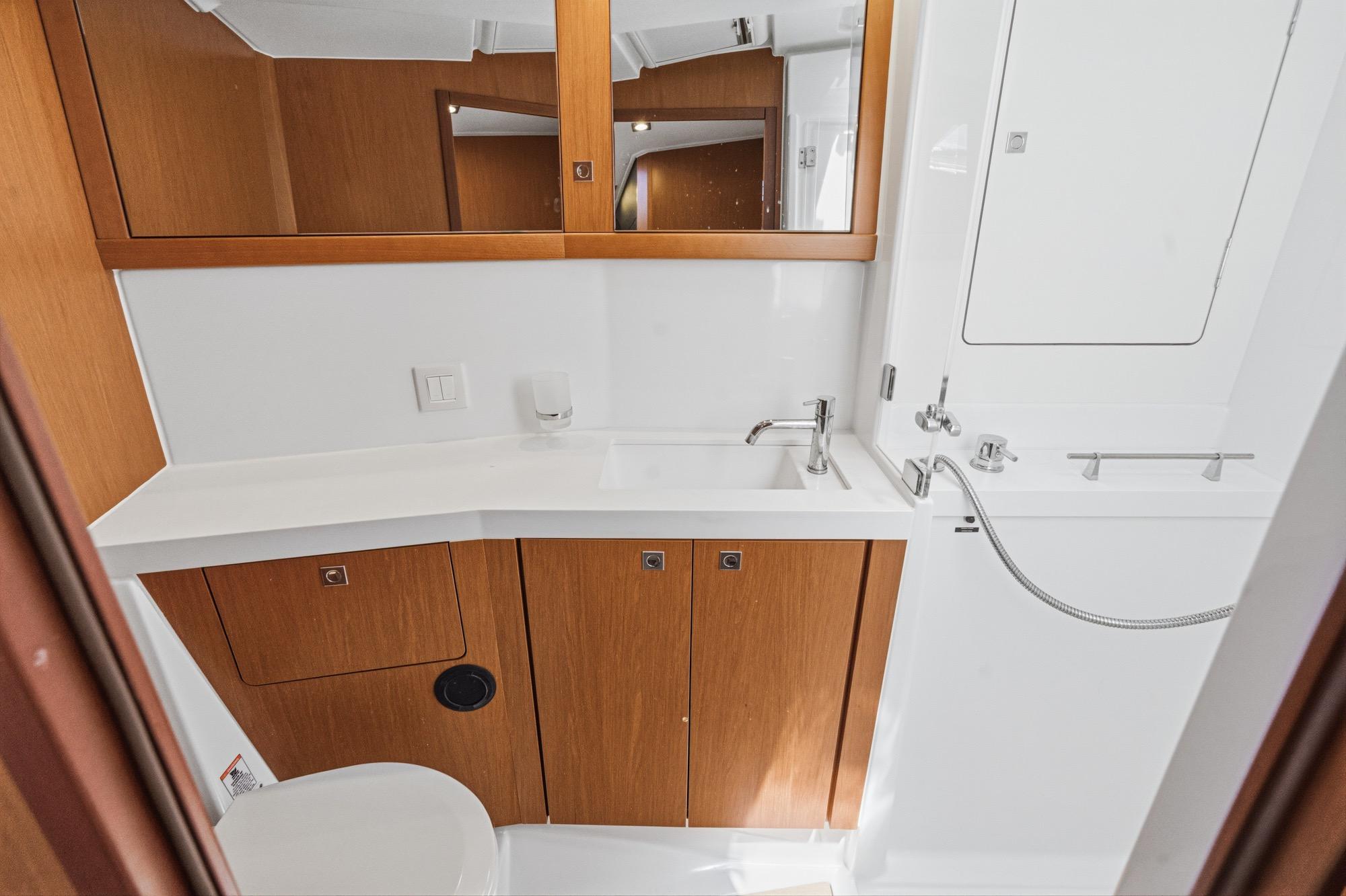 Bathroom interior of 2017 Beneteau Sense 50 yacht, featuring modern fixtures and wooden cabinetry.