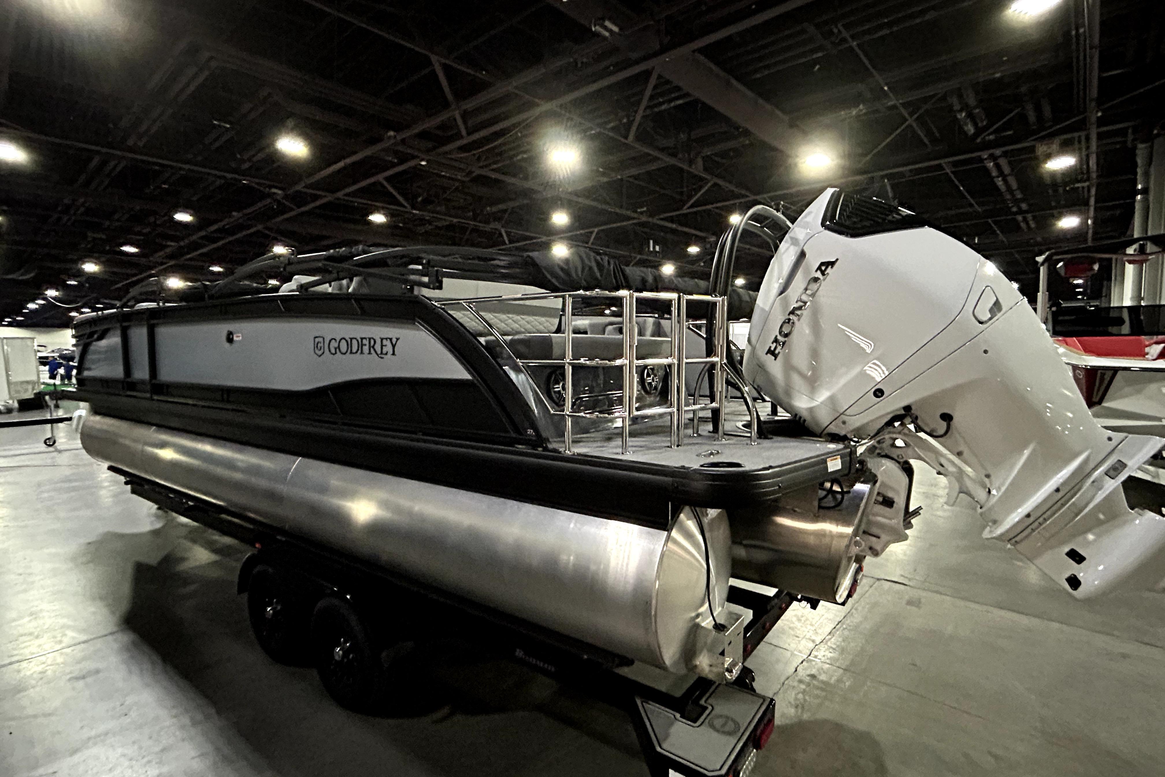 2026 Godfrey Monaco 255 QSL pontoon boat with Honda outboard motor in showroom.