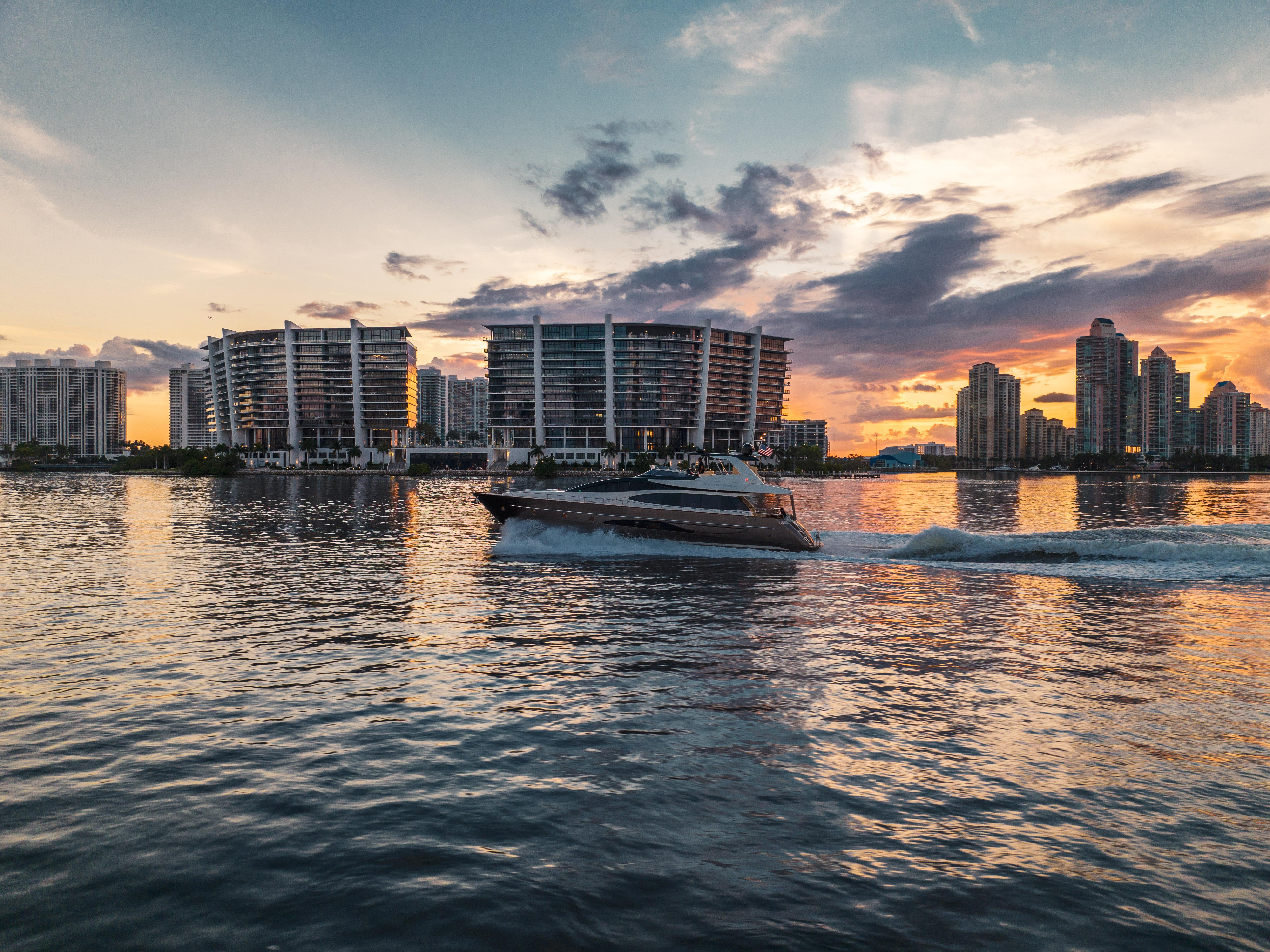 Luxury Riva 75 Venere yacht cruising at sunset near modern city skyline, 2012 model.