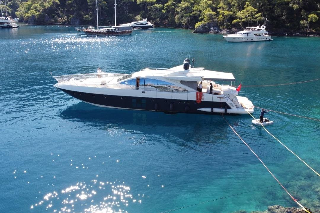 Luxury 2007 Azimut 86S yacht anchored in clear blue waters, surrounded by lush greenery.