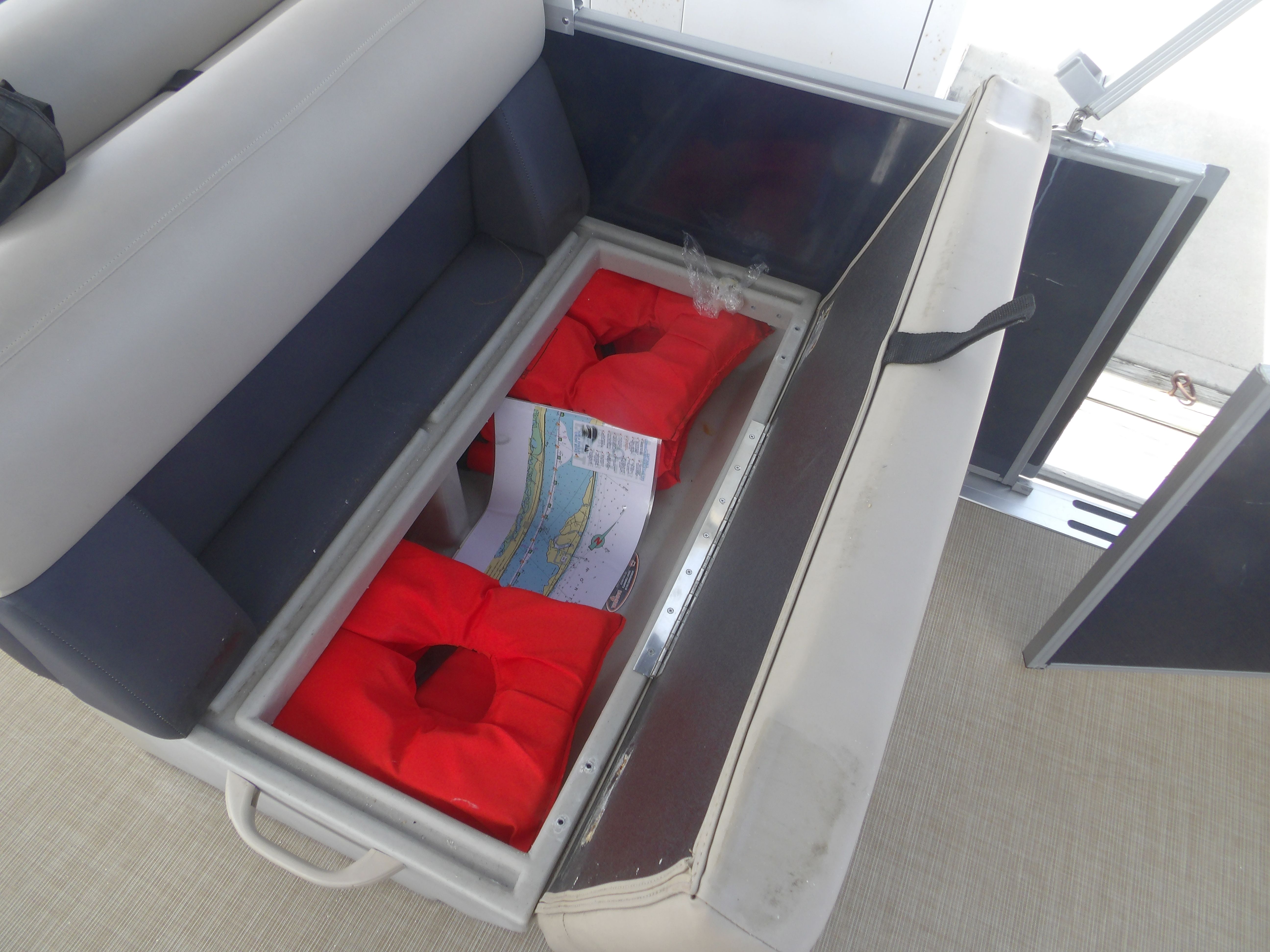 2024 Harris Pontoon seat storage with red life jackets.