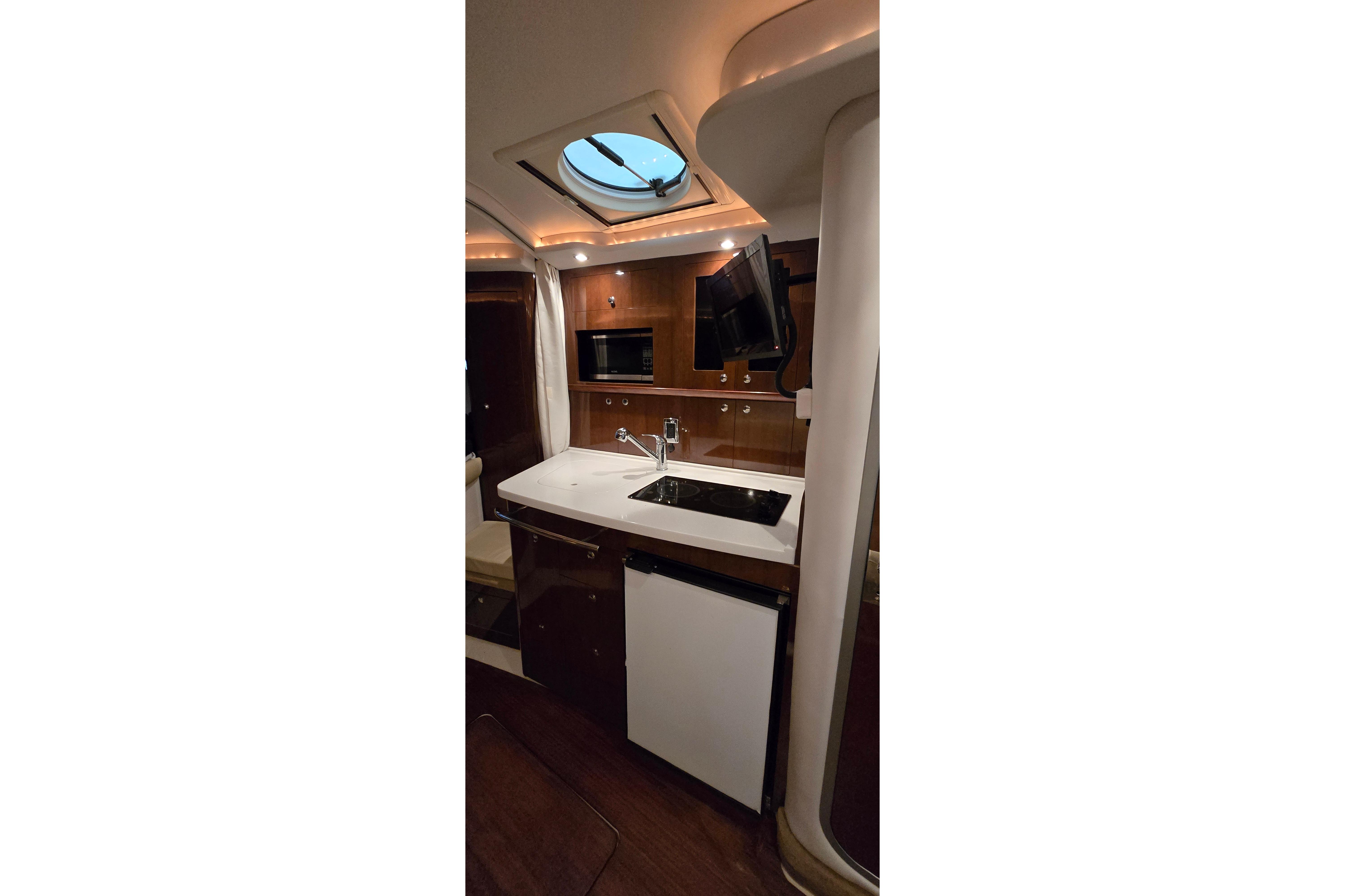 Interior of 2018 Four Winns V355 yacht featuring kitchenette with sink, microwave, and TV.