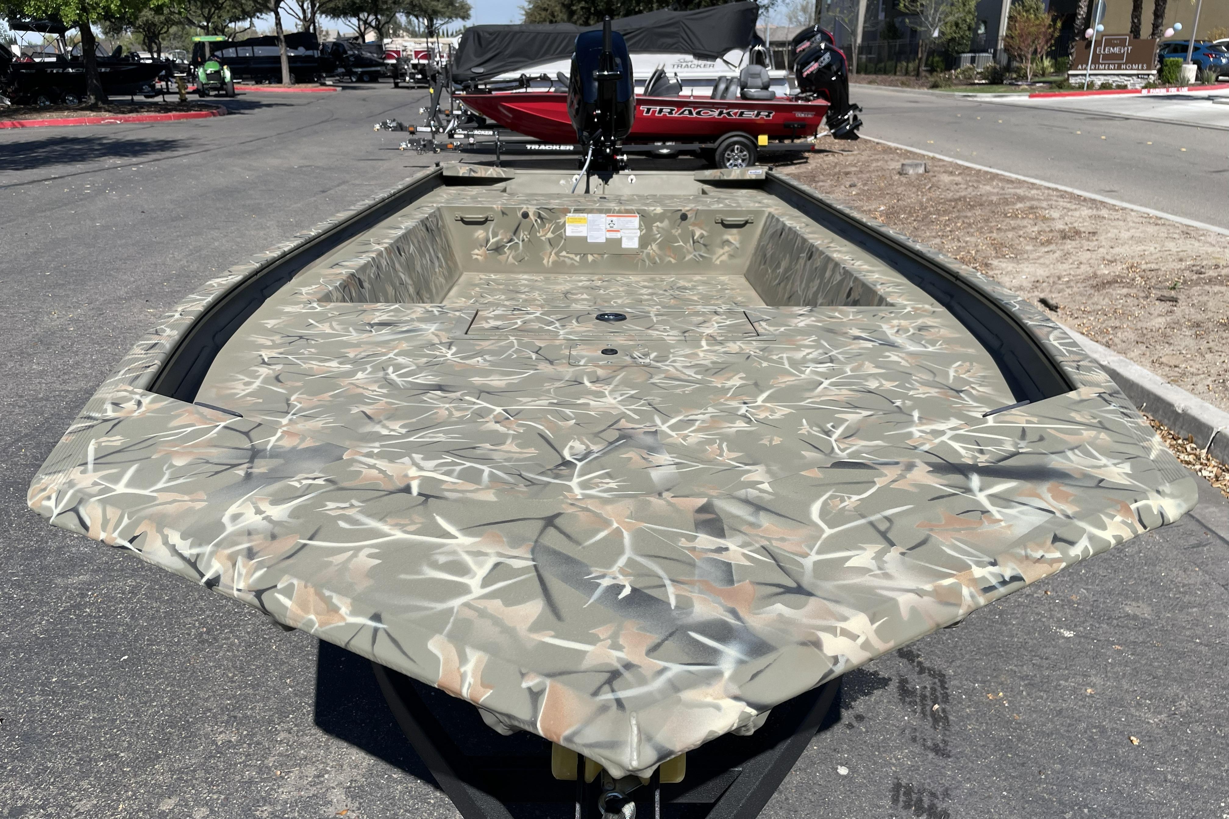 2025 Tracker Grizzly 1754 Jon boat with camouflage design in a parking lot.