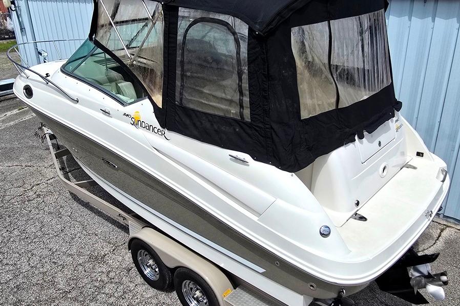 2006 Sea Ray 240 Sundancer boat on trailer, featuring black canopy and sleek design.