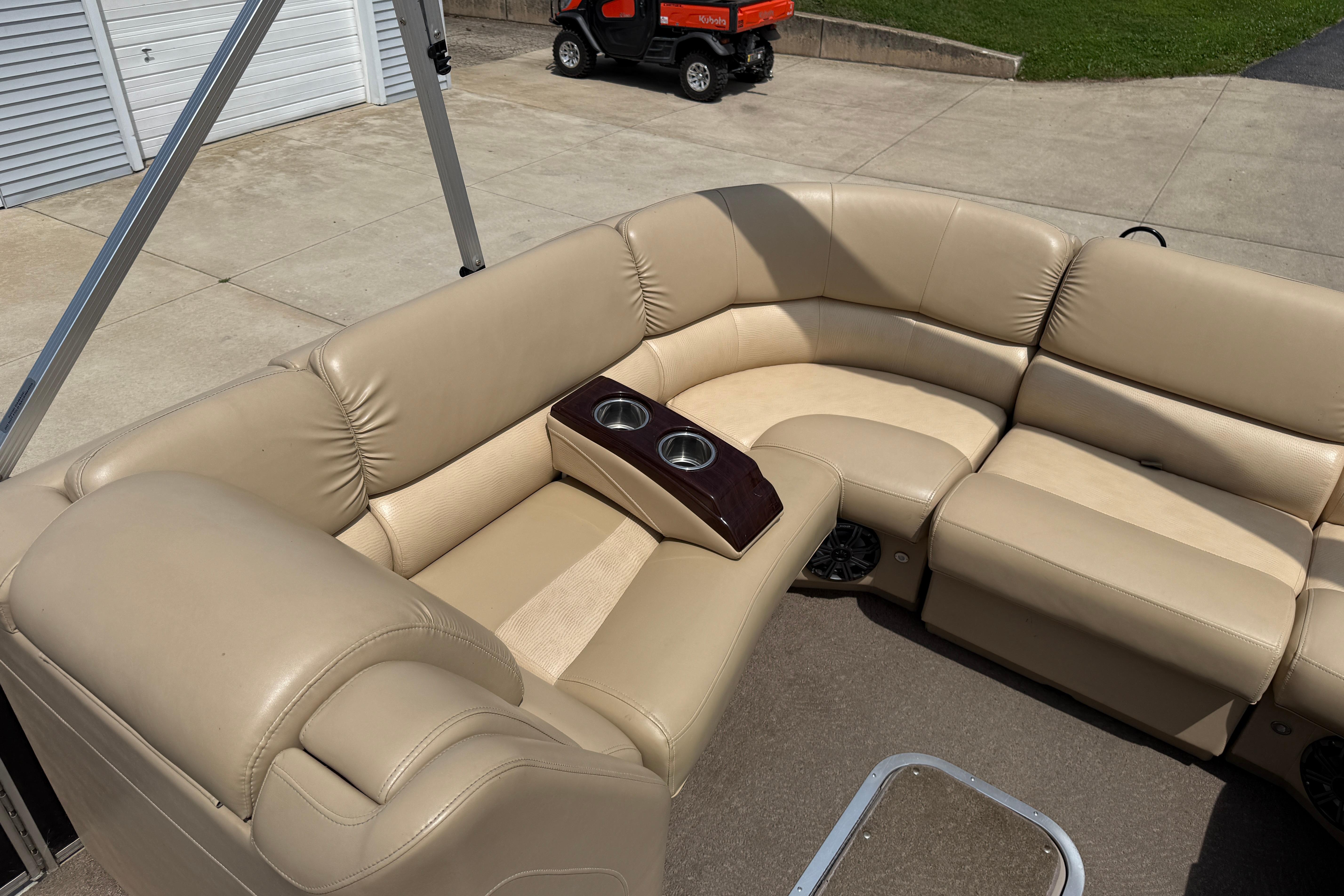 Luxurious beige seating on 2011 Bennington 2575QCW I/O pontoon boat with cup holders.