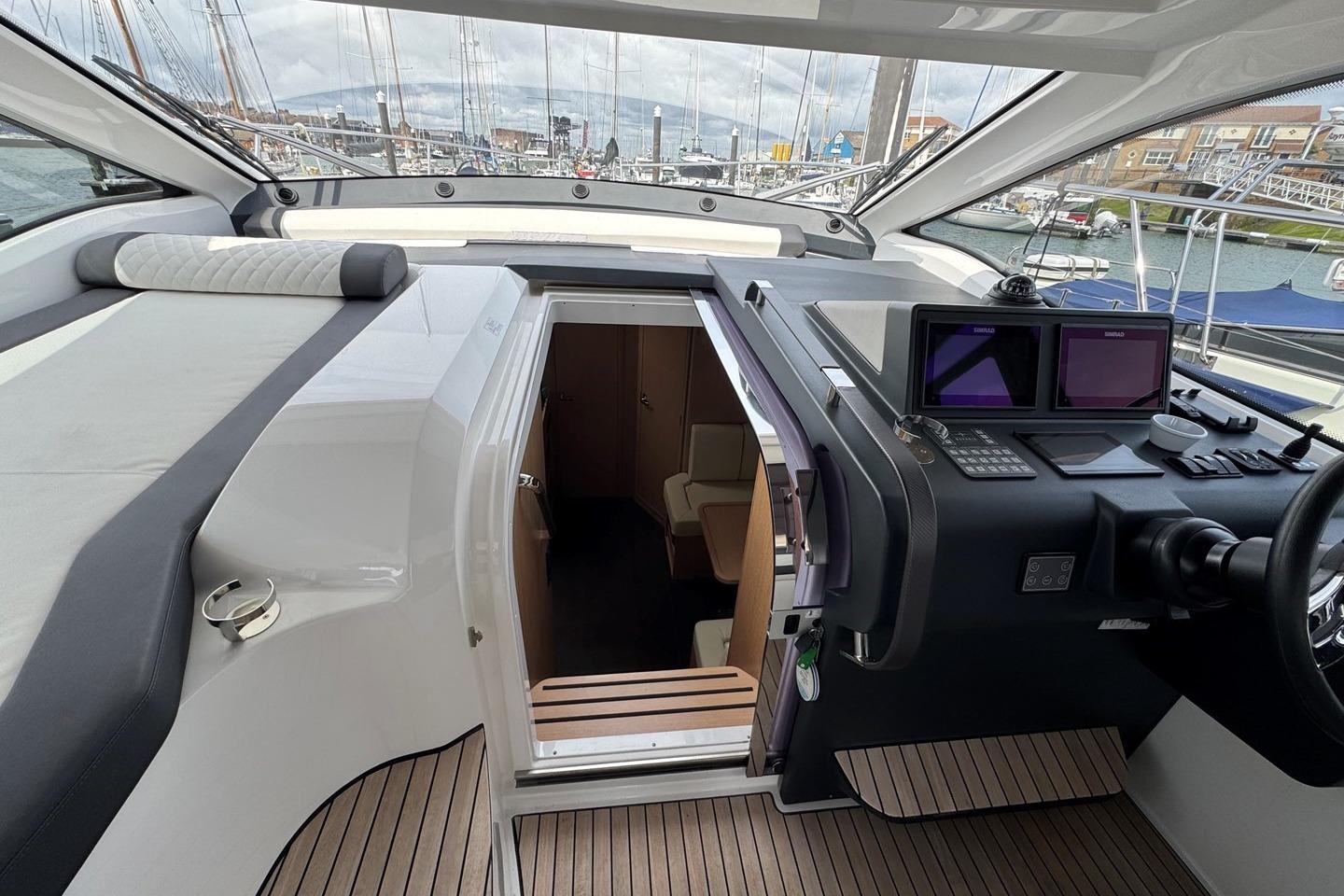 2023 Bavaria SR41 yacht interior with helm, navigation screens, and cabin entrance.