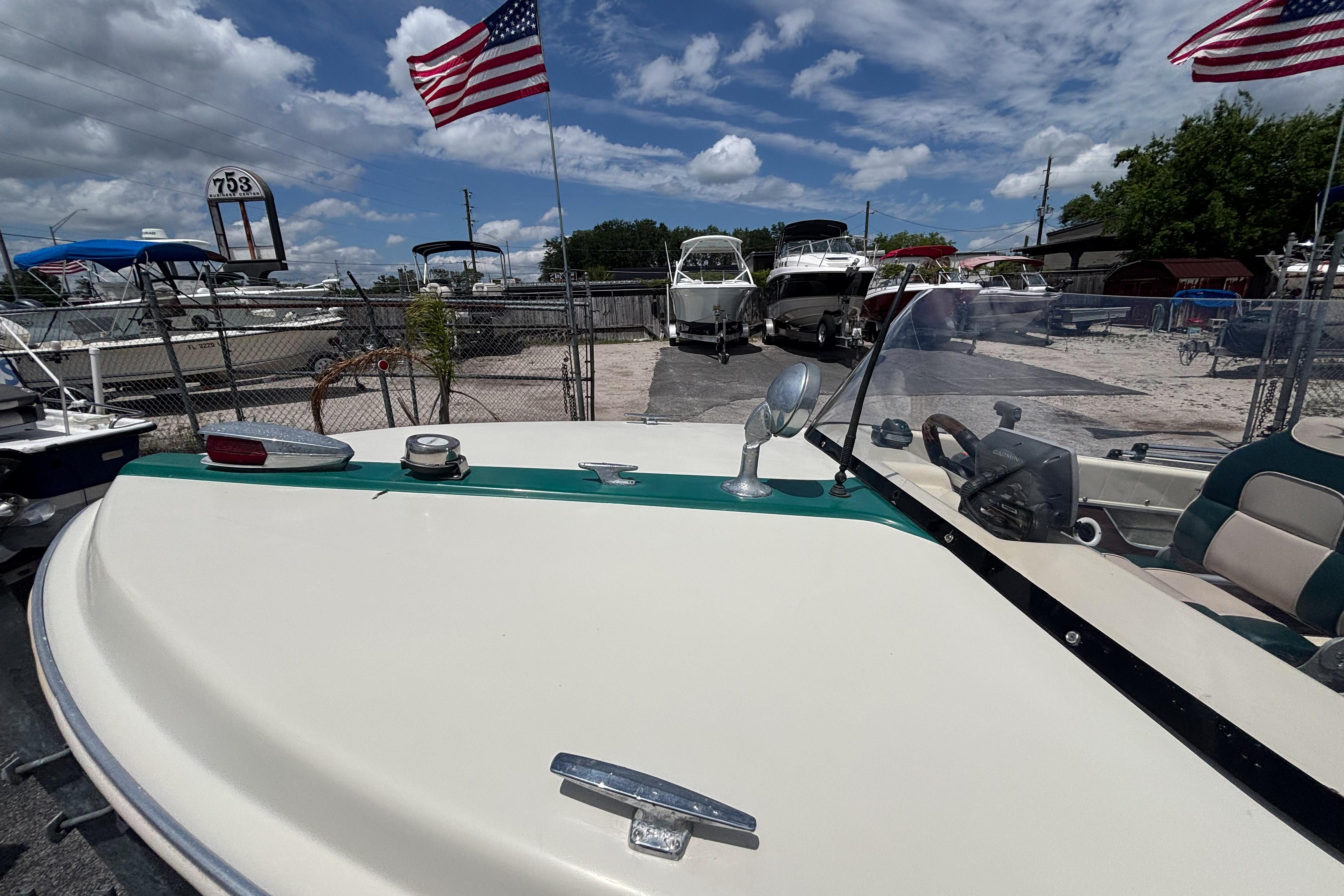 1966 Mohawk 15 boat with American flags, parked in a marina under a blue sky.