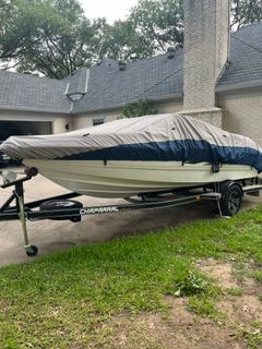 A 2004 Chaparral 190 SSi boat on a trailer, covered and parked in front of a house.