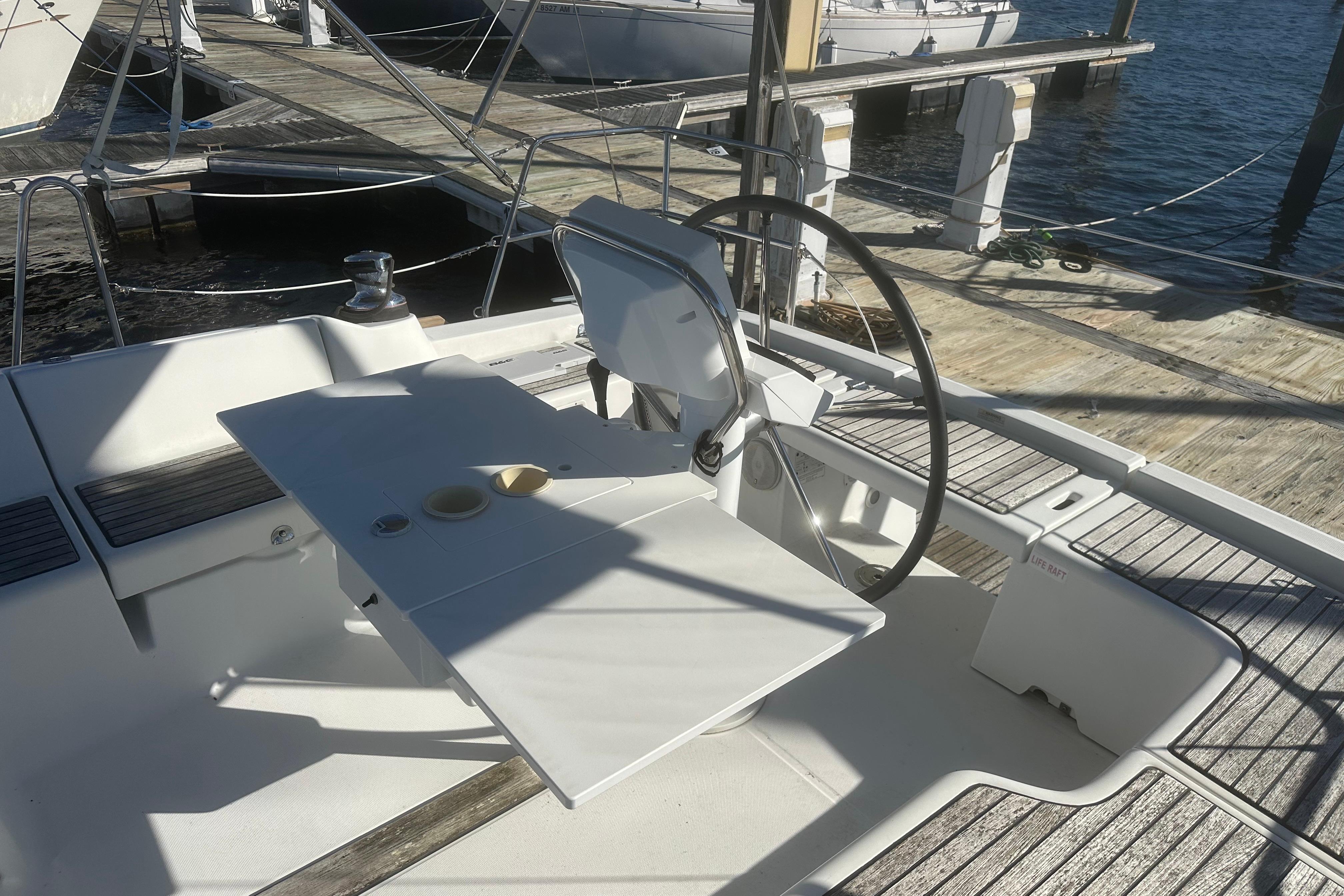 Cockpit of 2015 Beneteau Oceanis 37 sailboat with steering wheel and table, docked at marina.