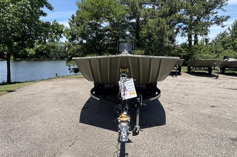 2026 Tracker Grizzly 2072 CC boat on trailer by a lake, surrounded by trees.
