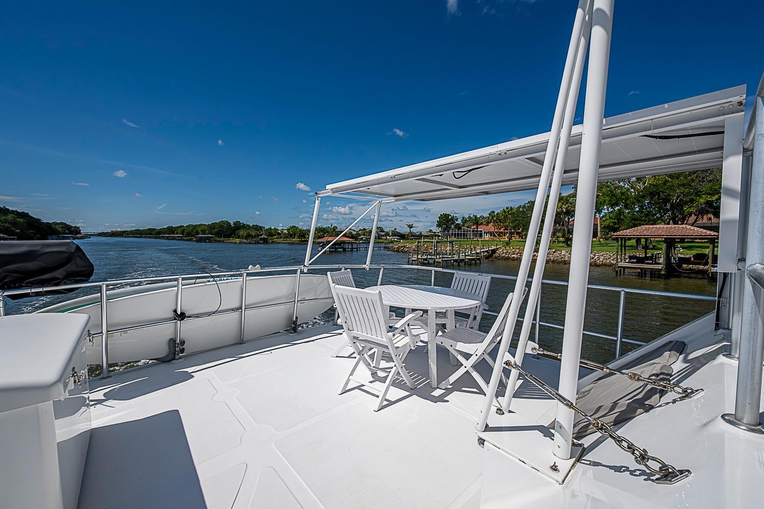 Deck view of 2003 Magna Marine Nova Scotia 47 yacht with outdoor seating and scenic waterway.