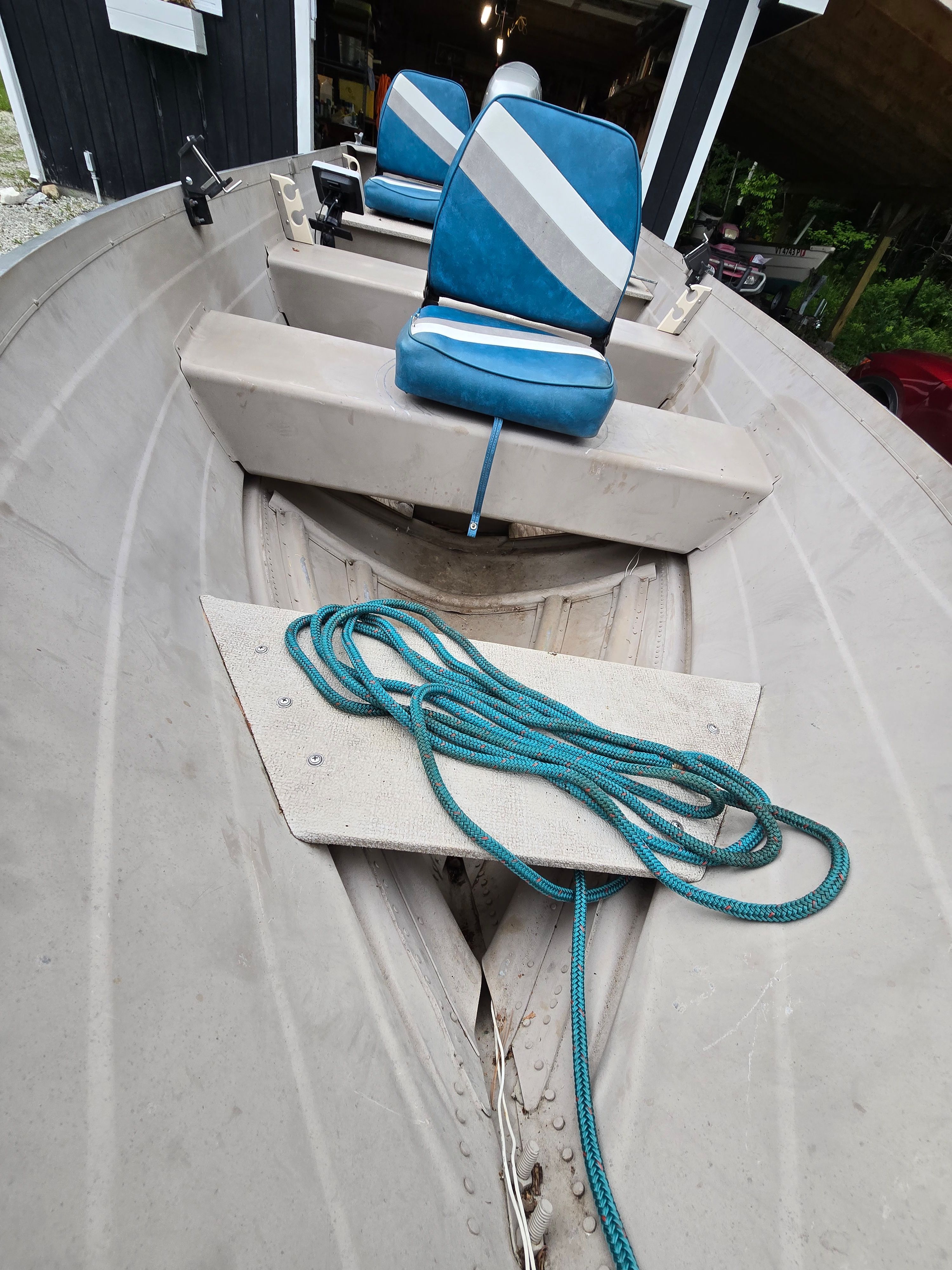 A gray boat with blue seats and a rope on the floor.