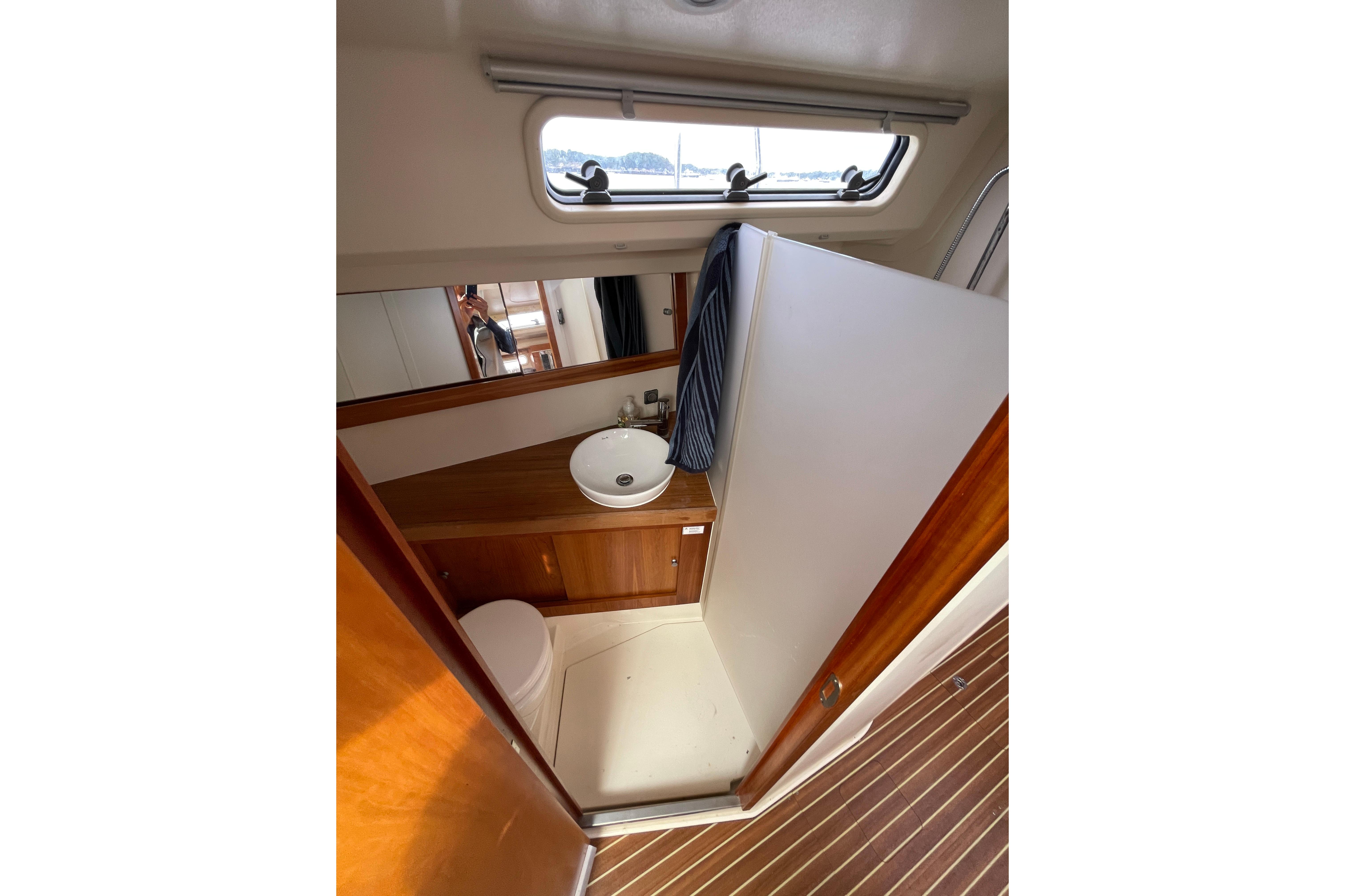 Interior of 2014 Hanse 415 yacht bathroom with sink, toilet, and wooden cabinetry.