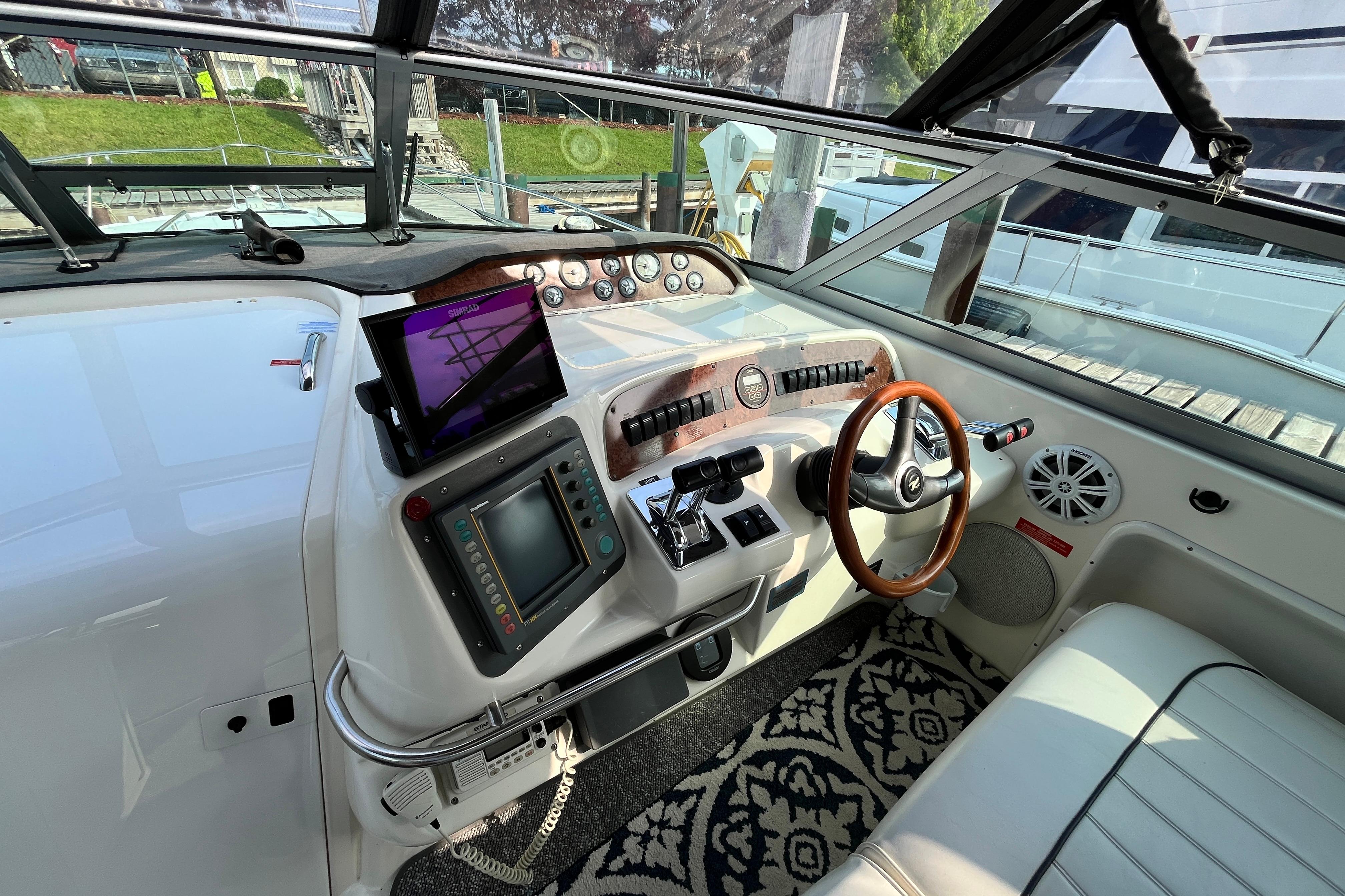Cockpit of a 1995 Sea Ray Sundancer 330 with modern navigation equipment and wooden steering wheel.