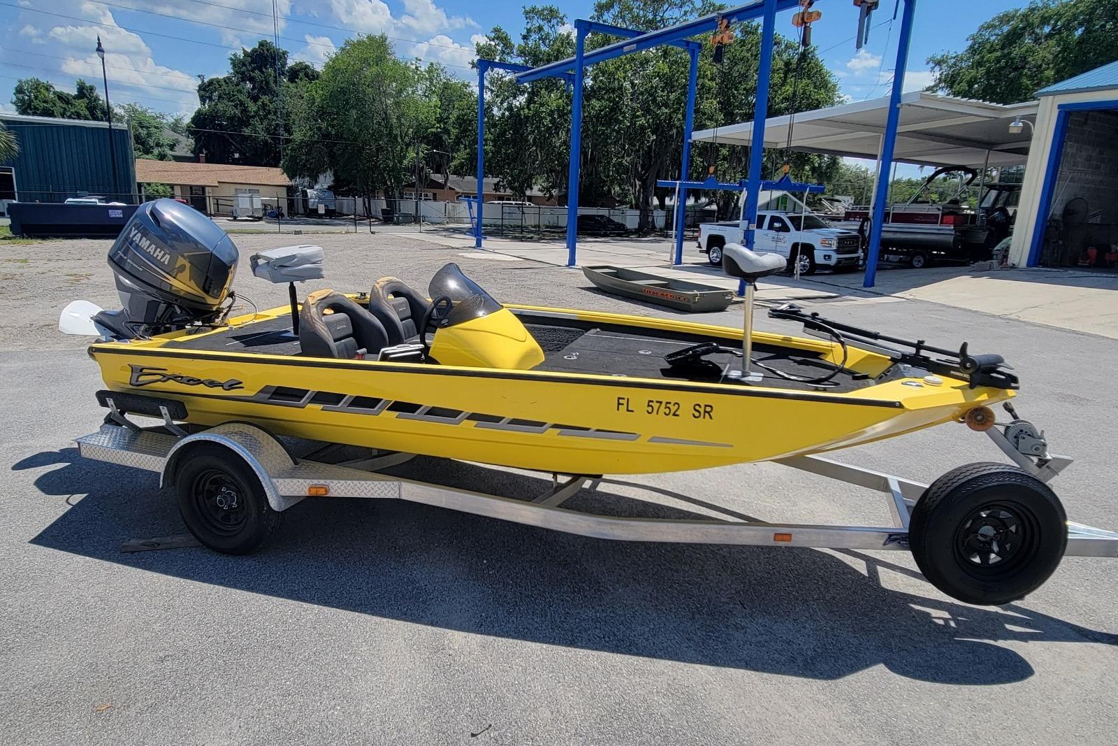 Yellow 2011 Excel 1751 F4 boat on trailer with Yamaha motor, parked outdoors.