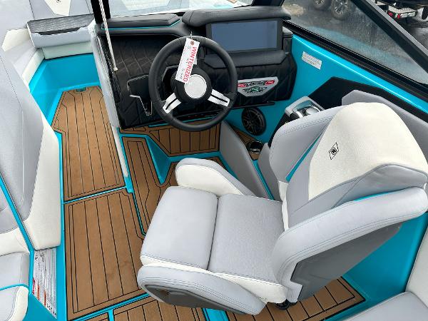 2022 Nautique S23 boat interior with captain's chair, steering wheel, and touchscreen display.