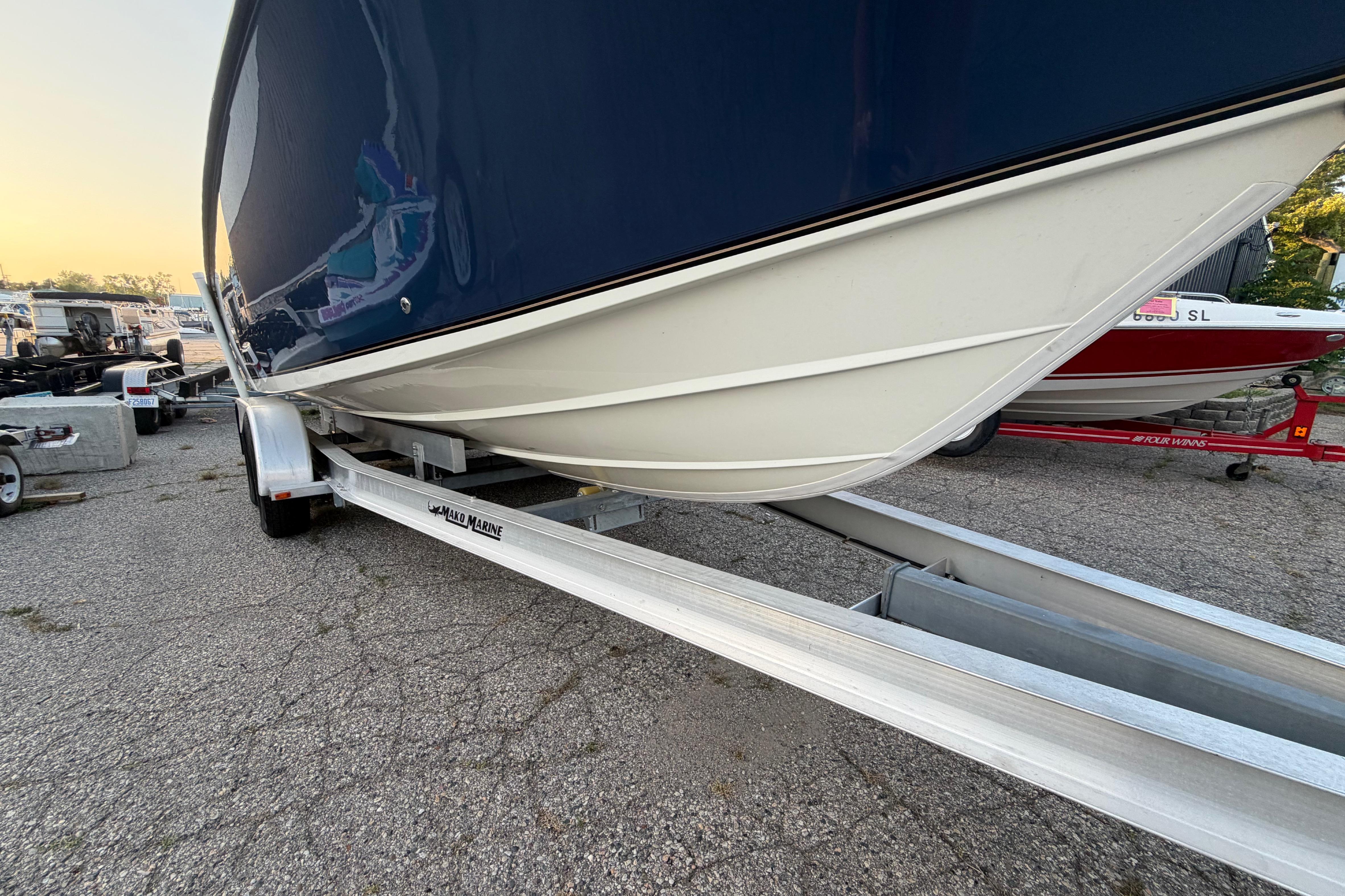 2007 Mako 234 Center Console boat on trailer, parked outdoors at sunset.